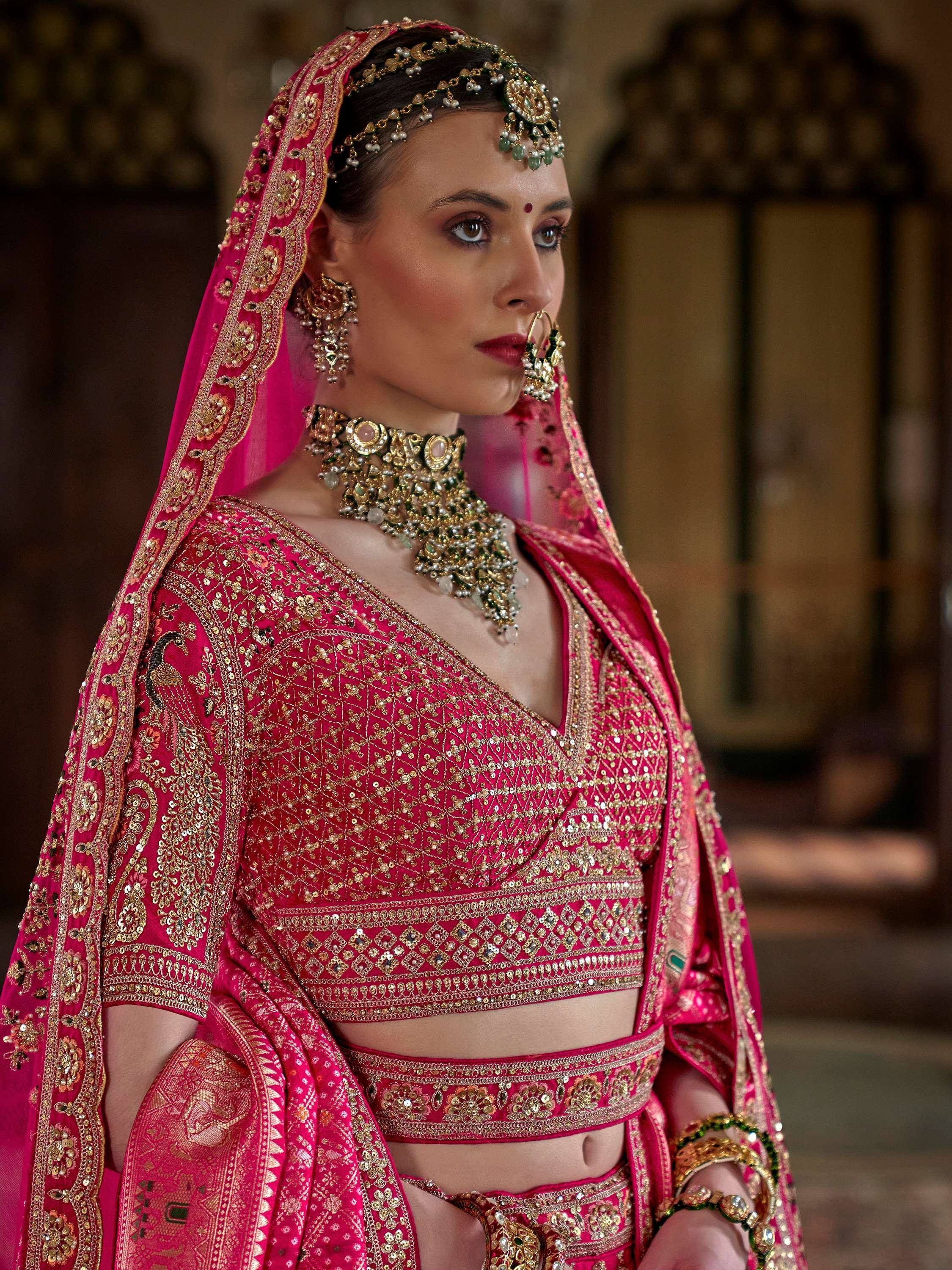Elegant pink designer lehenga choli with gold embroidery and traditional Indian bridal jewelry