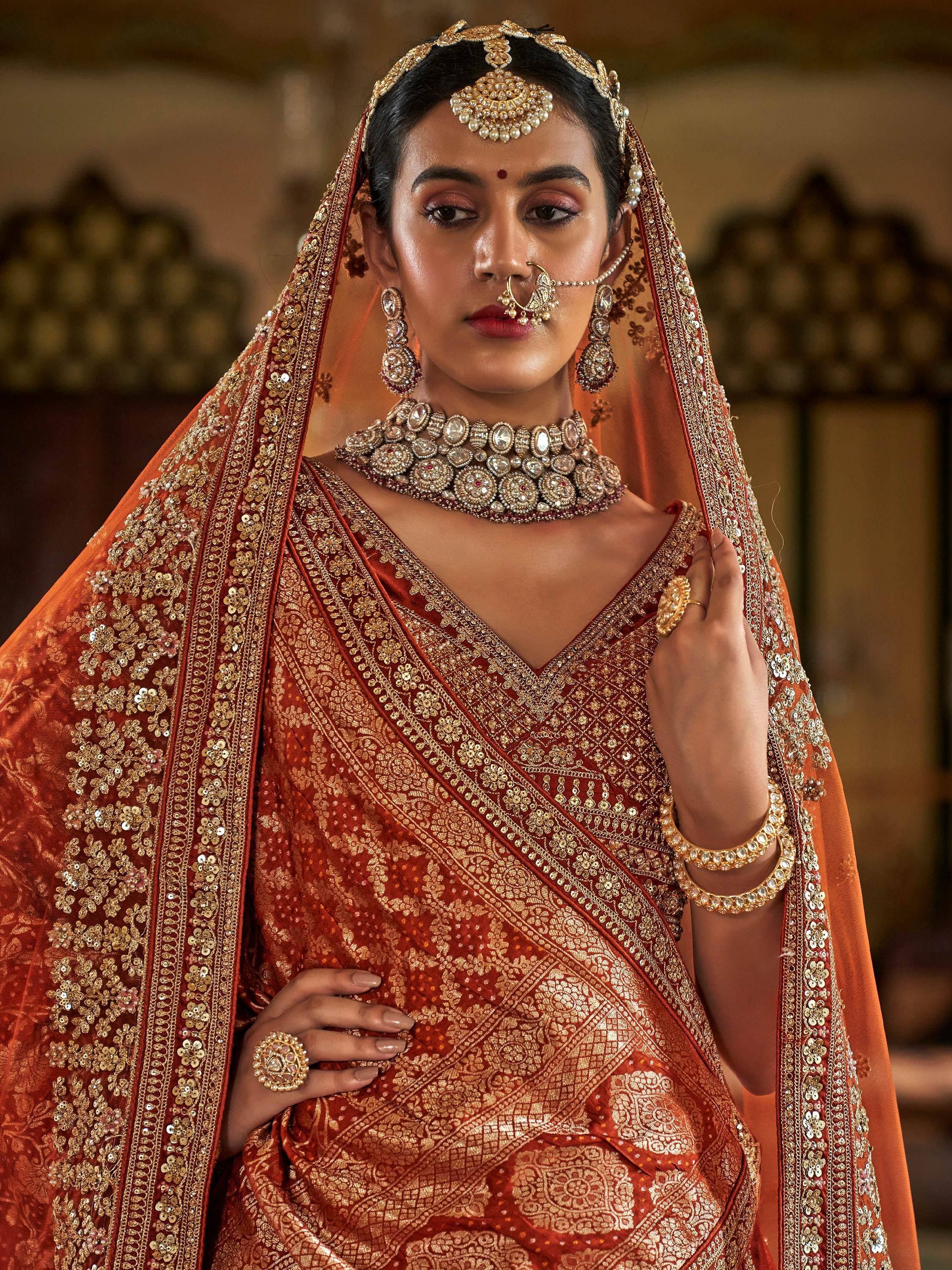 Elegant Indian bride in ornate red and gold lehenga with heavy jewelry and dupatta