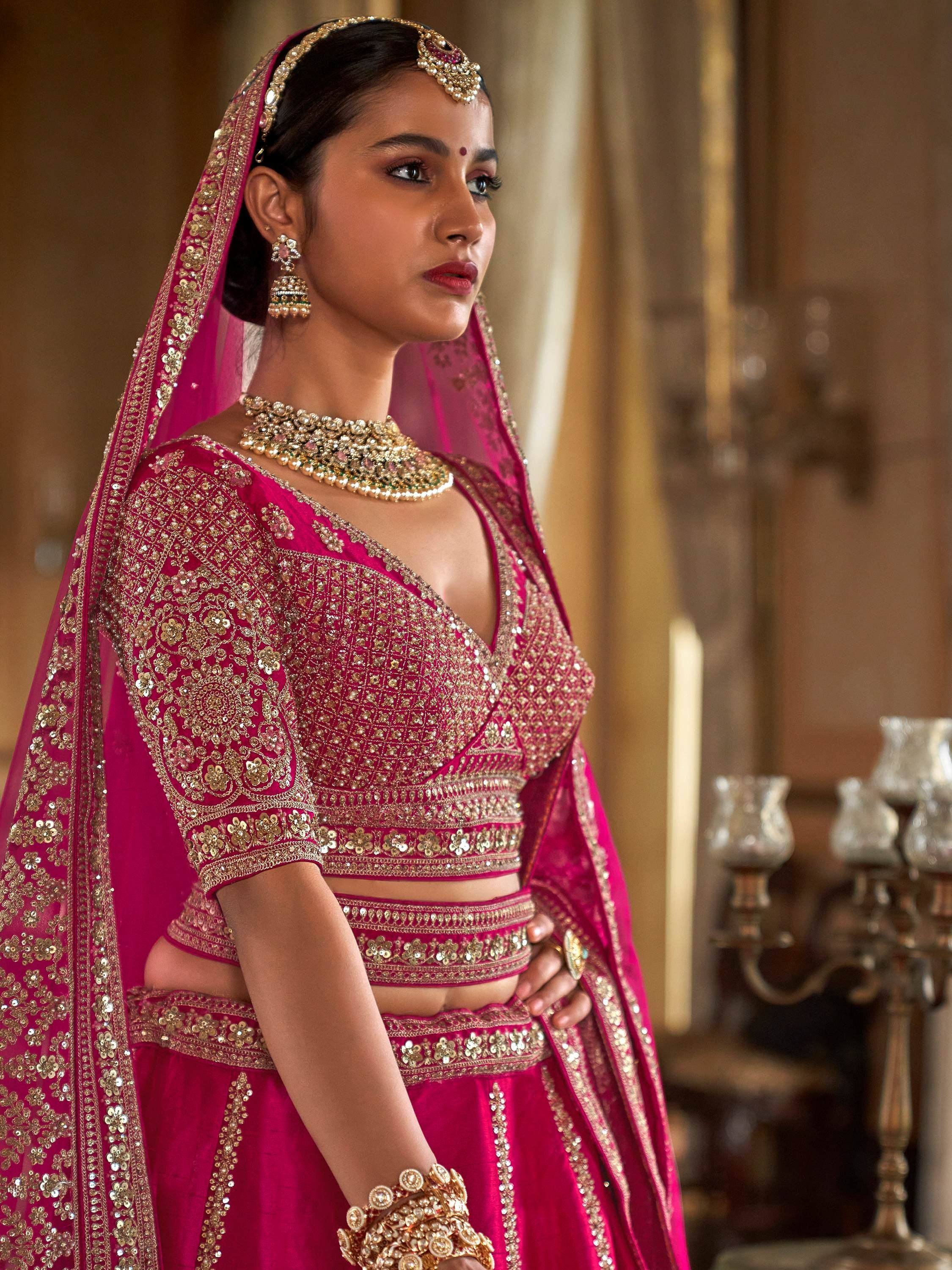Pink designer lehenga choli with gold embroidery and traditional Indian bridal jewelry