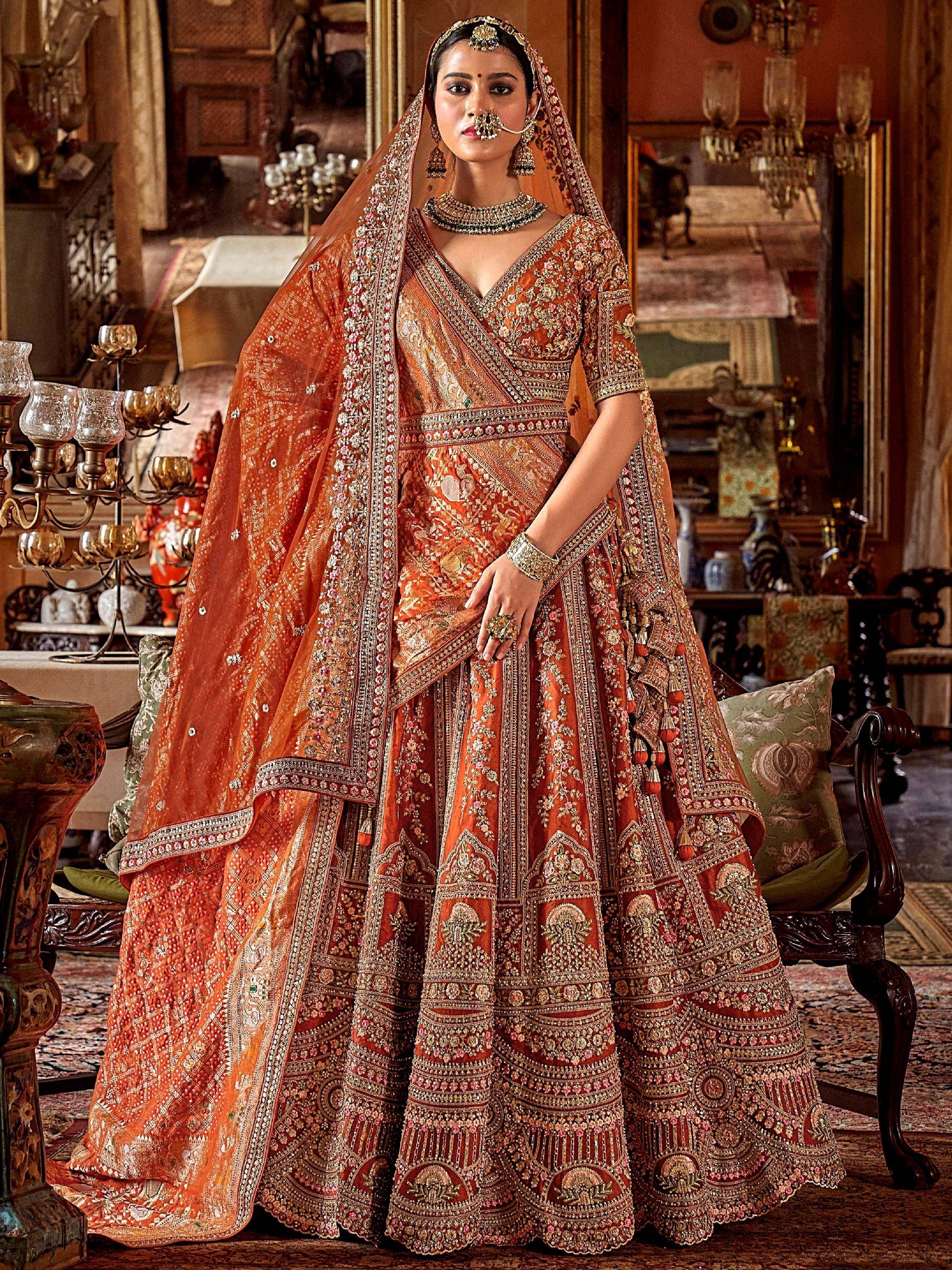 Elegant orange designer lehenga choli with heavy embroidery, perfect for Indian weddings and festive occasions.