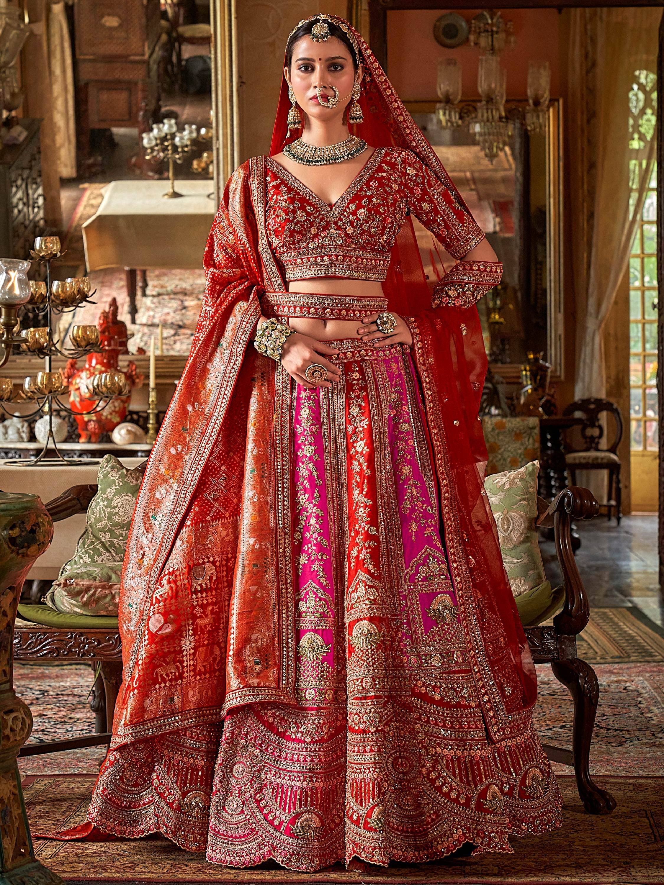 Red and pink embroidered lehenga choli with heavy gold work, perfect for Indian weddings and festive occasions.