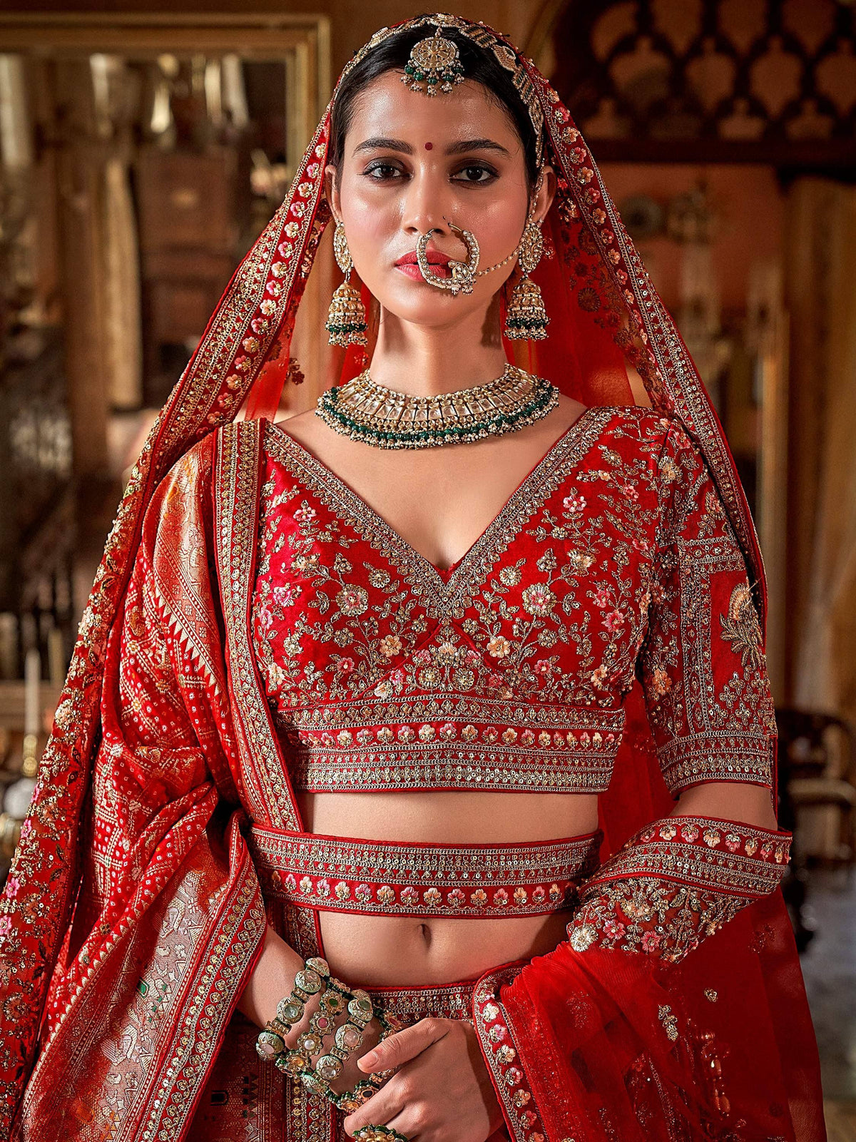 Red embroidered lehenga choli with gold detailing, traditional Indian bridal wear, heavy jewelry set