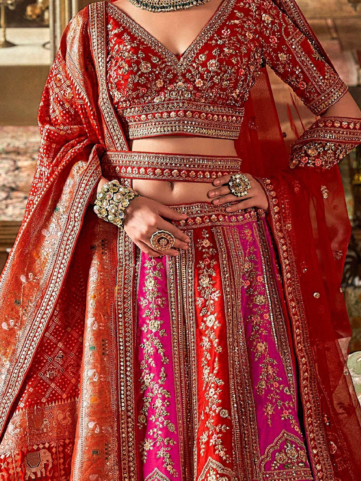 Red and pink embroidered lehenga choli with gold detailing, perfect for Indian weddings and festive occasions.