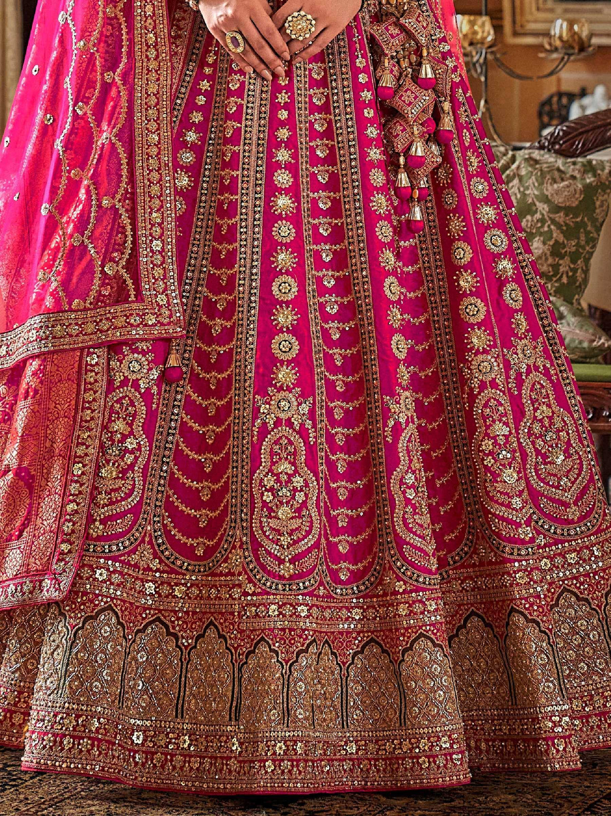 Fuchsia pink lehenga choli with heavy gold embroidery and sequin work, perfect for Indian weddings and festive occasions.