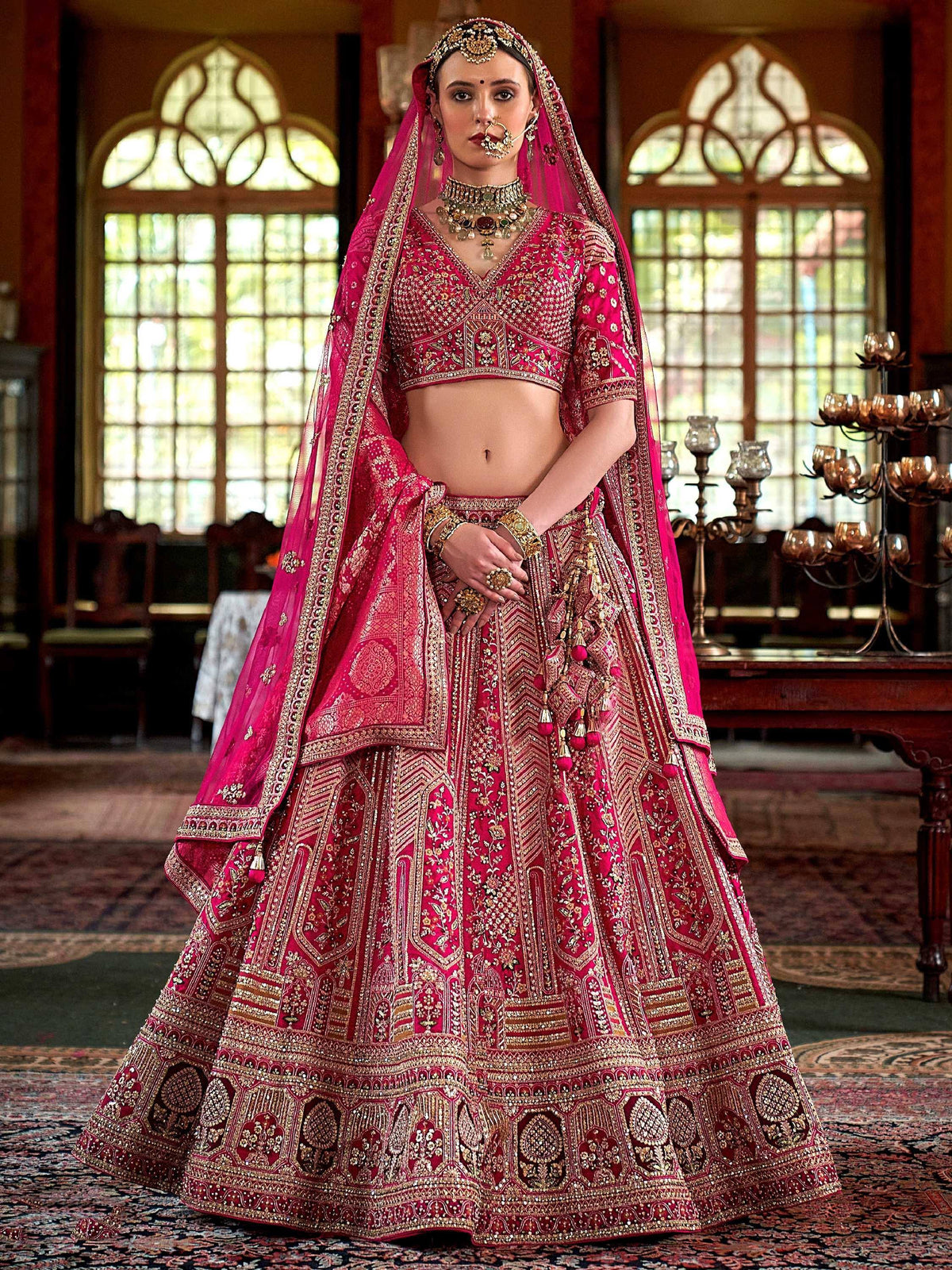 Fuchsia designer lehenga choli with heavy gold embroidery, perfect for Indian weddings and ethnic events.