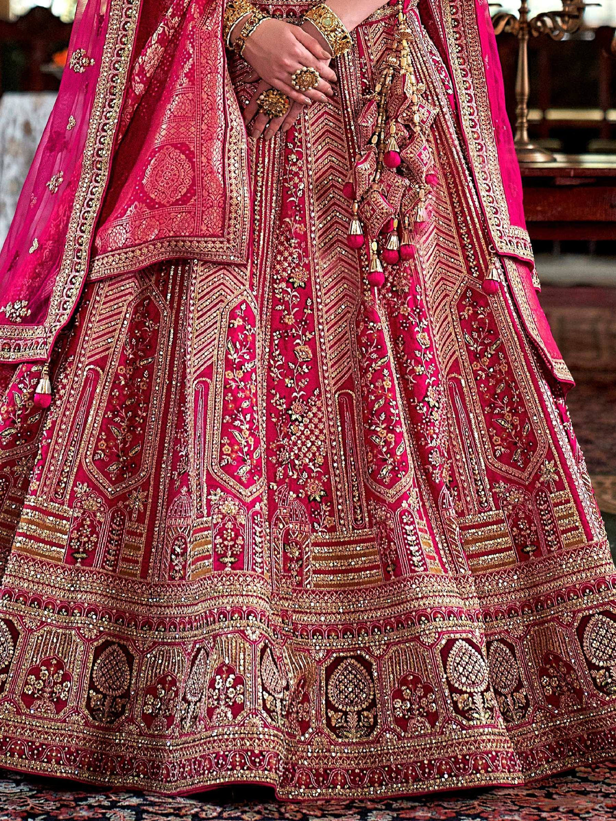 Luxury pink lehenga choli with heavy gold embroidery and tassels, perfect for Indian weddings and festive occasions.