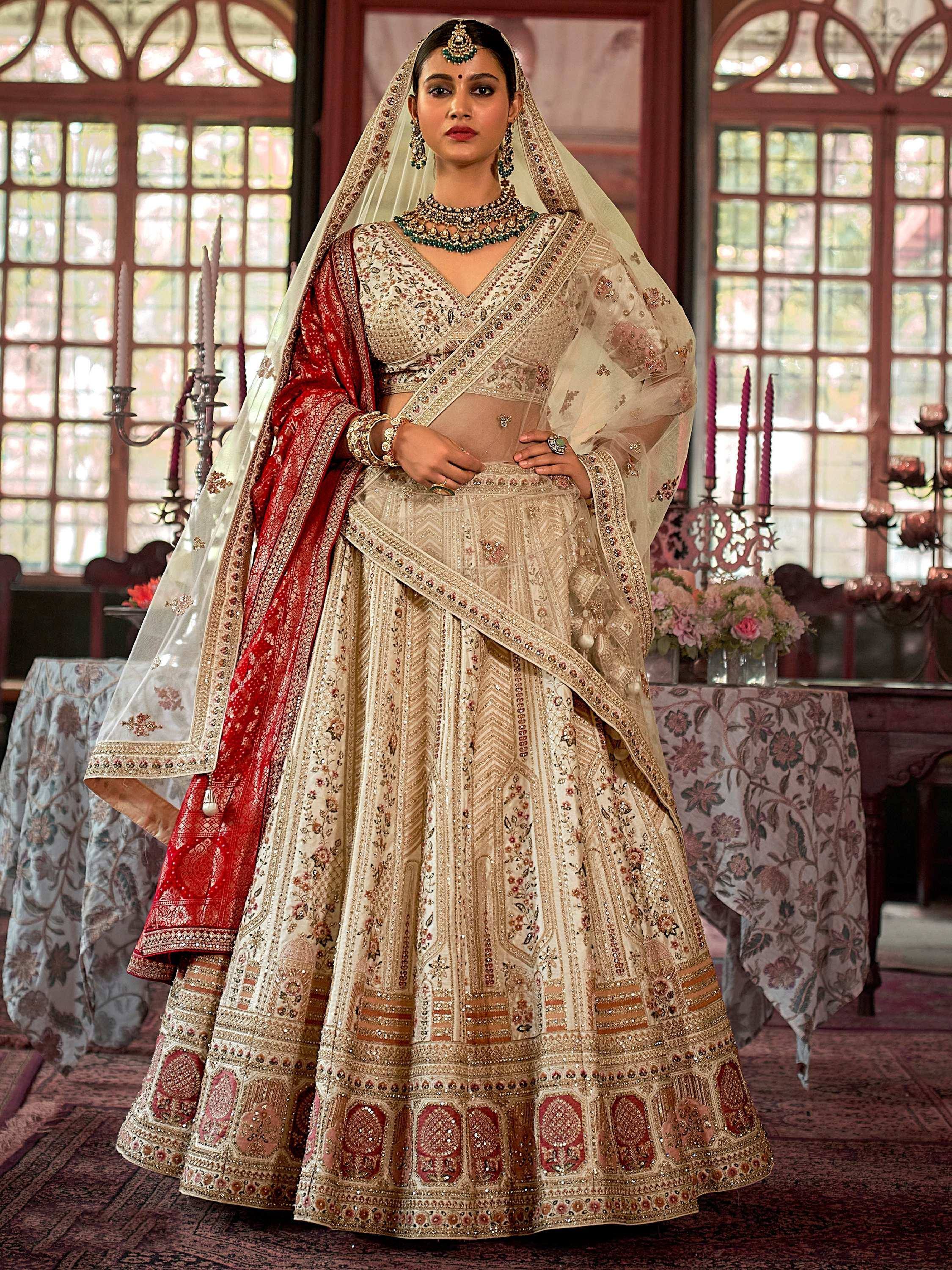 Elegant ivory and red embroidered lehenga choli with dupatta, perfect for Indian weddings and festive occasions.