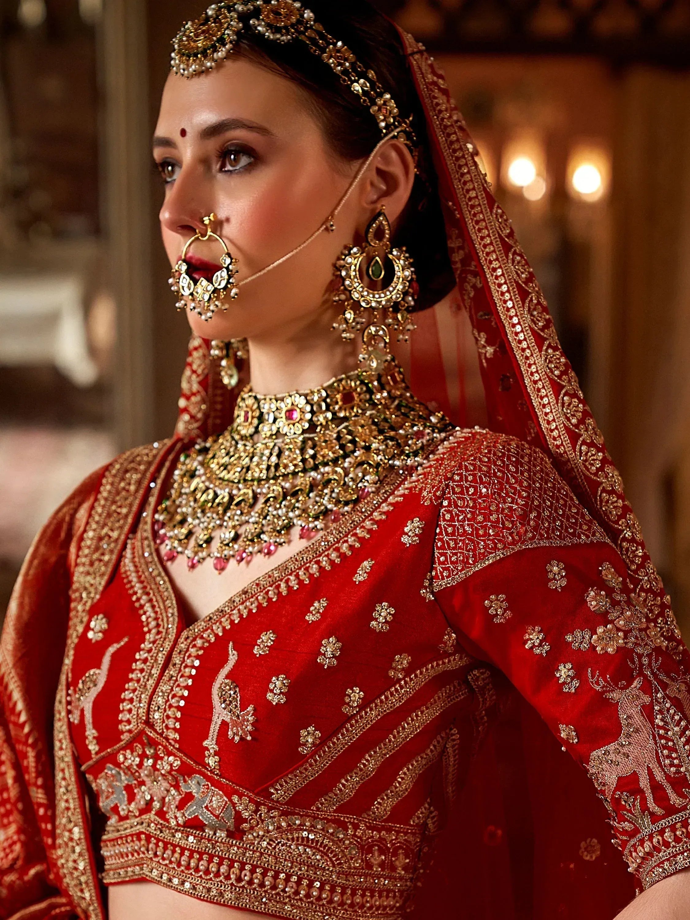 Red bridal lehenga choli with gold embroidery, heavy jewelry, and traditional Indian wedding attire