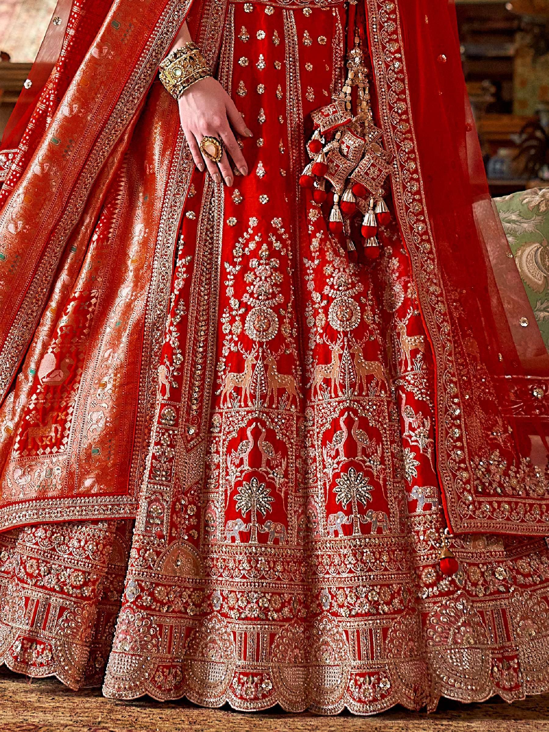 Red embroidered lehenga choli with deer and peacock motifs, heavy zari work, and traditional Indian bridal jewelry