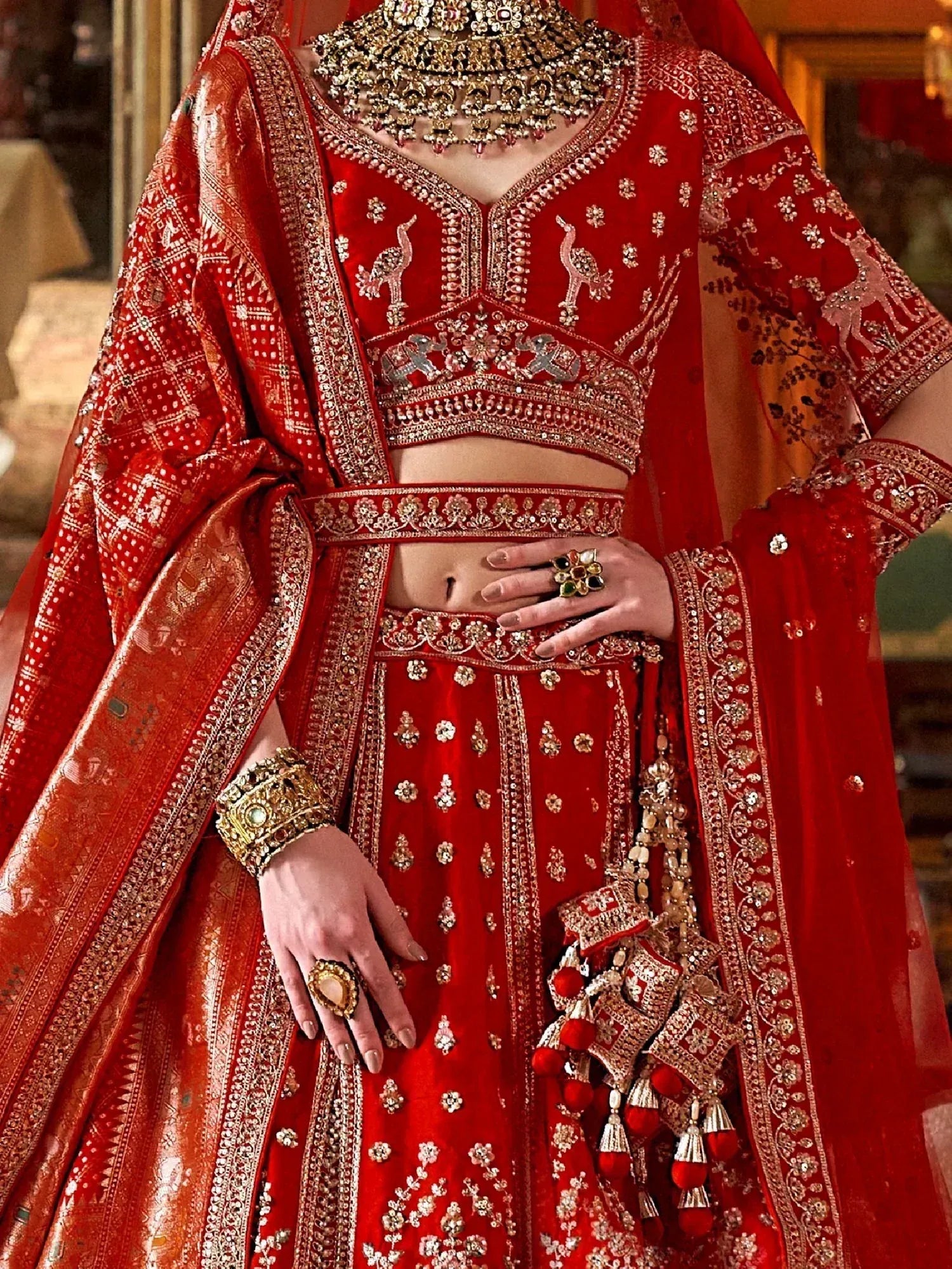 Red bridal lehenga choli with heavy gold embroidery, peacock motifs, and traditional Indian jewelry
