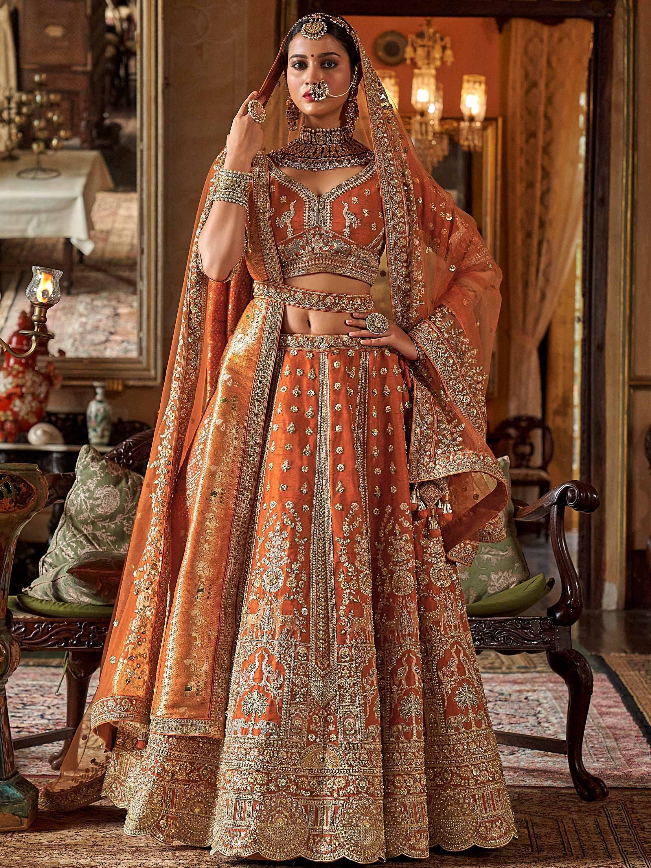 Orange embroidered lehenga choli with heavy gold work, perfect for Indian weddings and festive occasions.