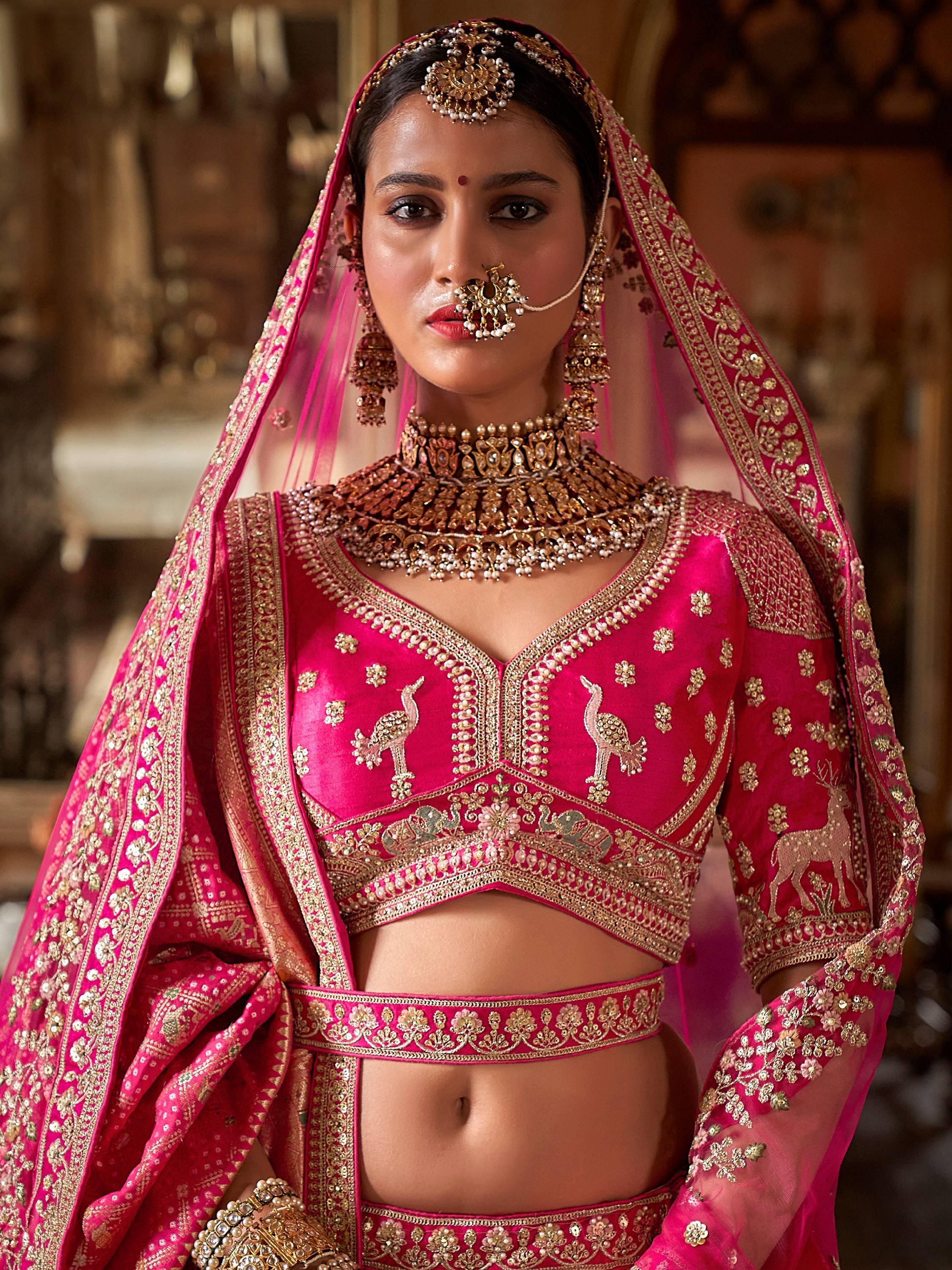 Pink embroidered lehenga choli with gold detailing, traditional Indian bridal wear, heavy jewelry