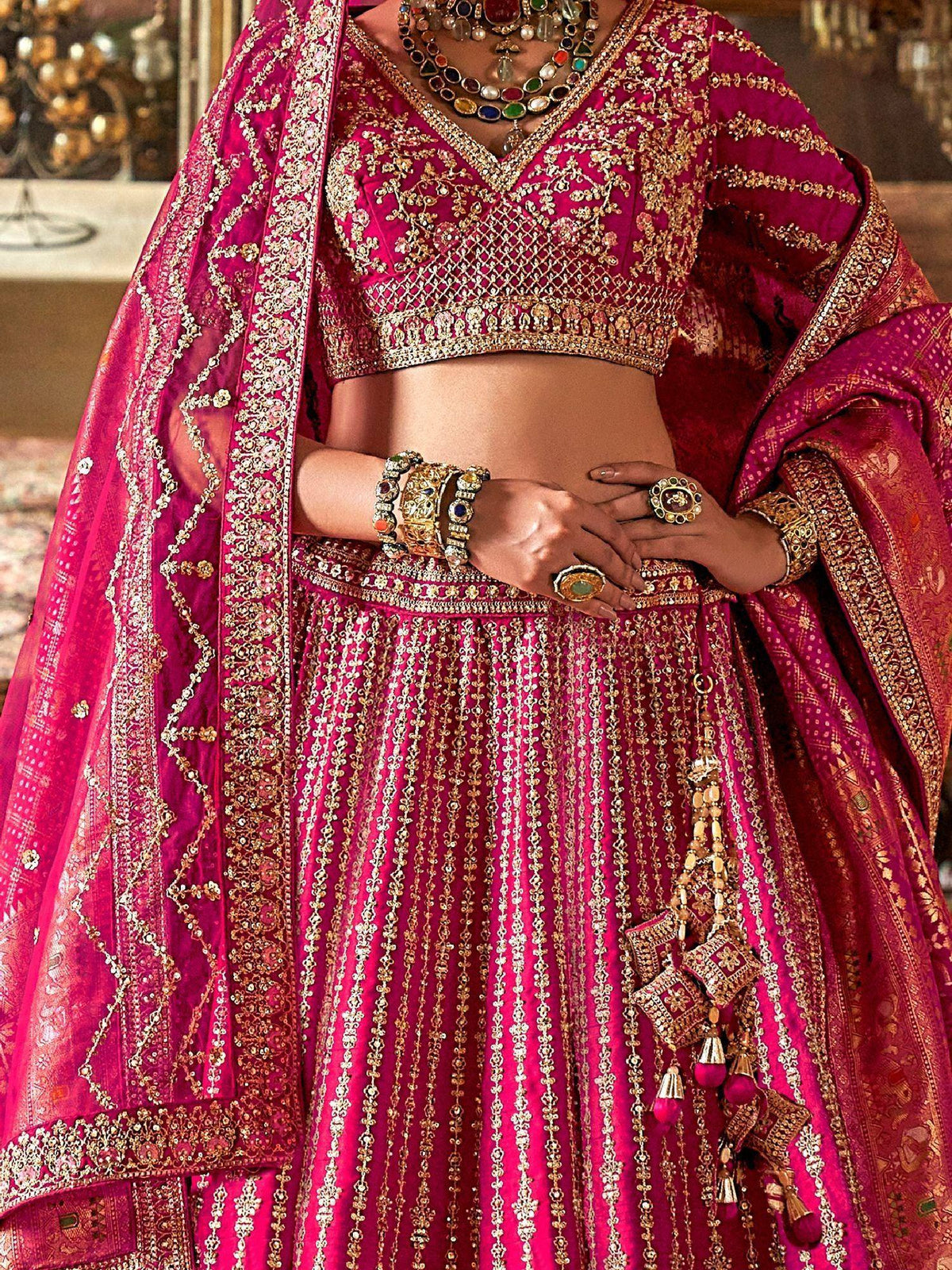 Fuchsia pink designer lehenga choli with heavy gold embroidery and traditional jewelry
