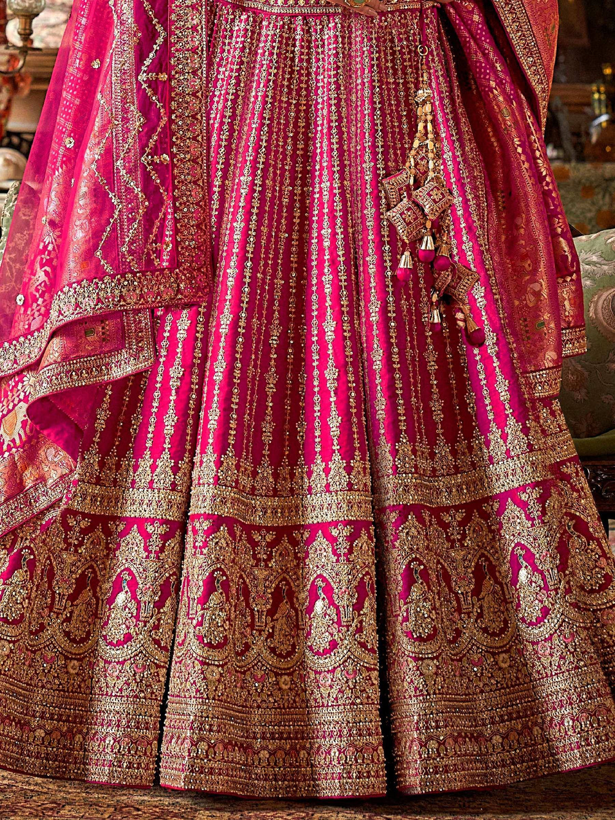 Fuchsia pink designer lehenga choli with heavy gold embroidery and peacock motifs, perfect for weddings.