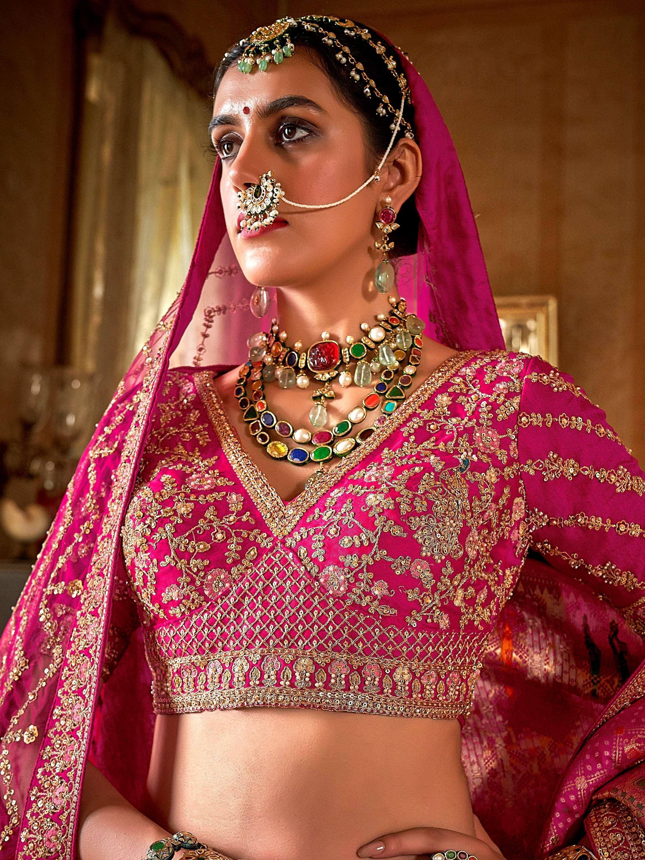 Pink embroidered lehenga choli with gold detailing, statement jewelry, and traditional Indian bridal accessories