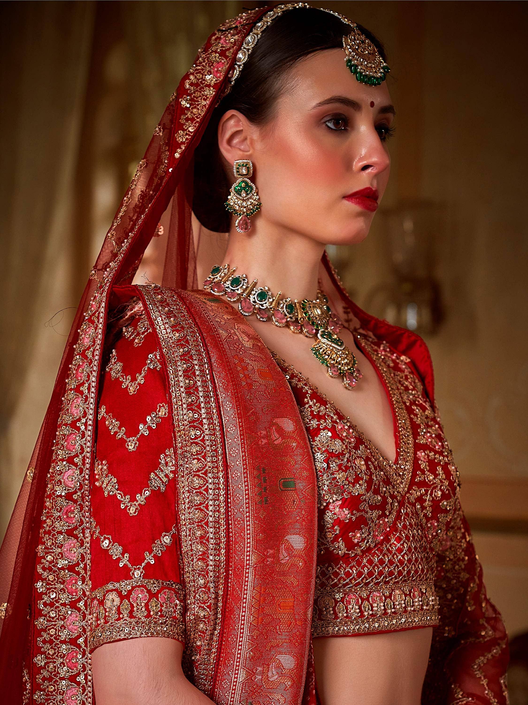 Red embroidered lehenga choli with gold detailing, matching dupatta, and traditional Indian bridal jewelry