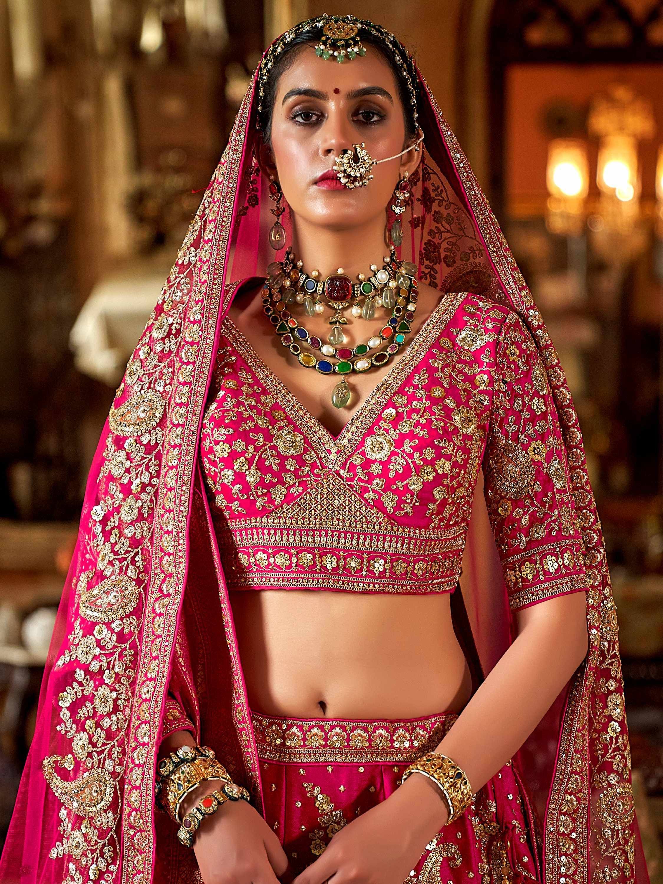 Pink embroidered lehenga choli with gold detailing, traditional Indian bridal wear, complete with jewelry and dupatta