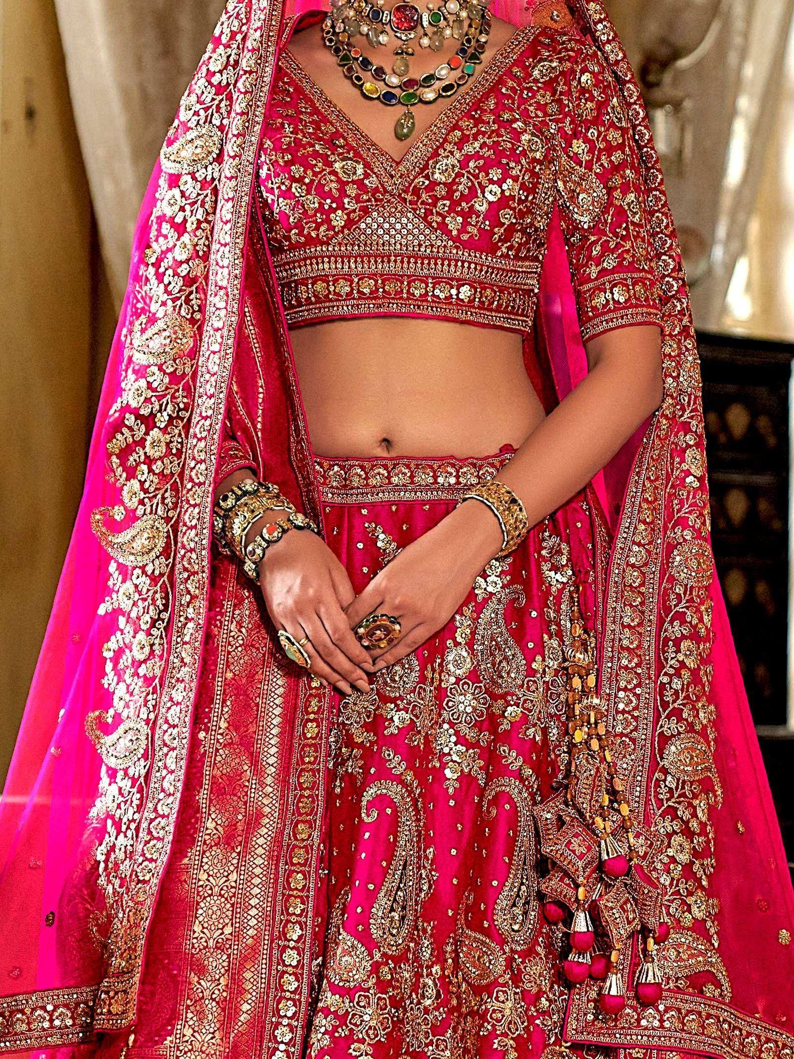 Fuchsia pink designer lehenga choli with gold embroidery and matching dupatta, perfect for Indian weddings.