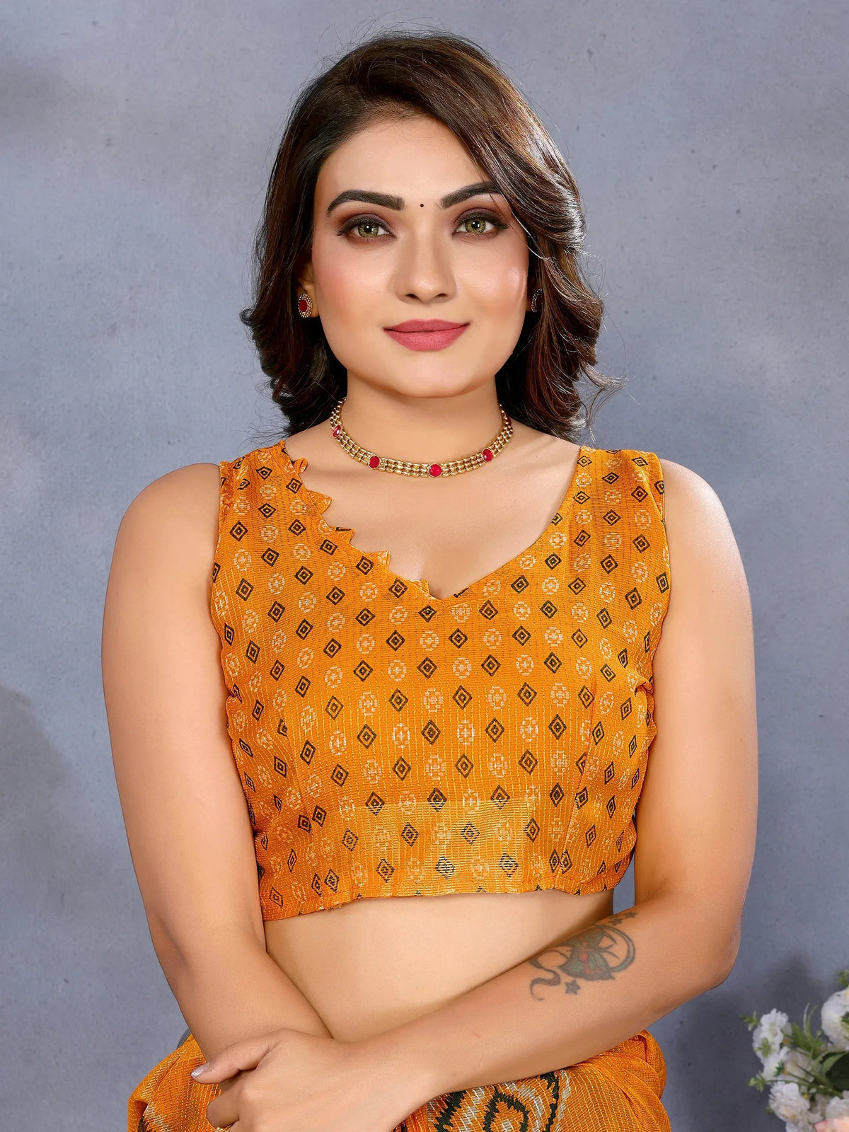 Orange printed sleeveless blouse with geometric patterns, paired with ethnic jewelry for festive wear