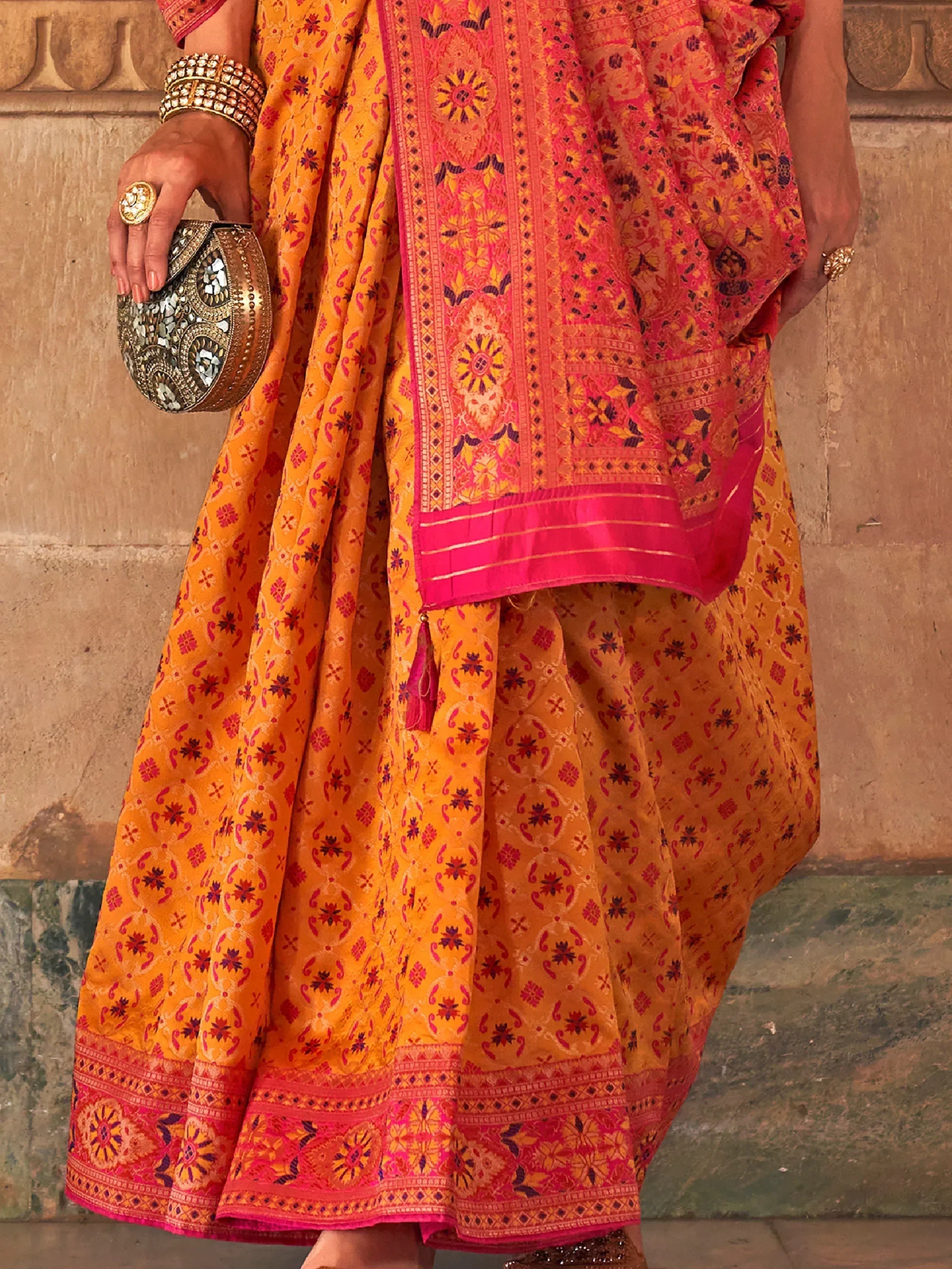 Vibrant orange and pink printed Indian ethnic lehenga choli with mirror work clutch and gold jewelry