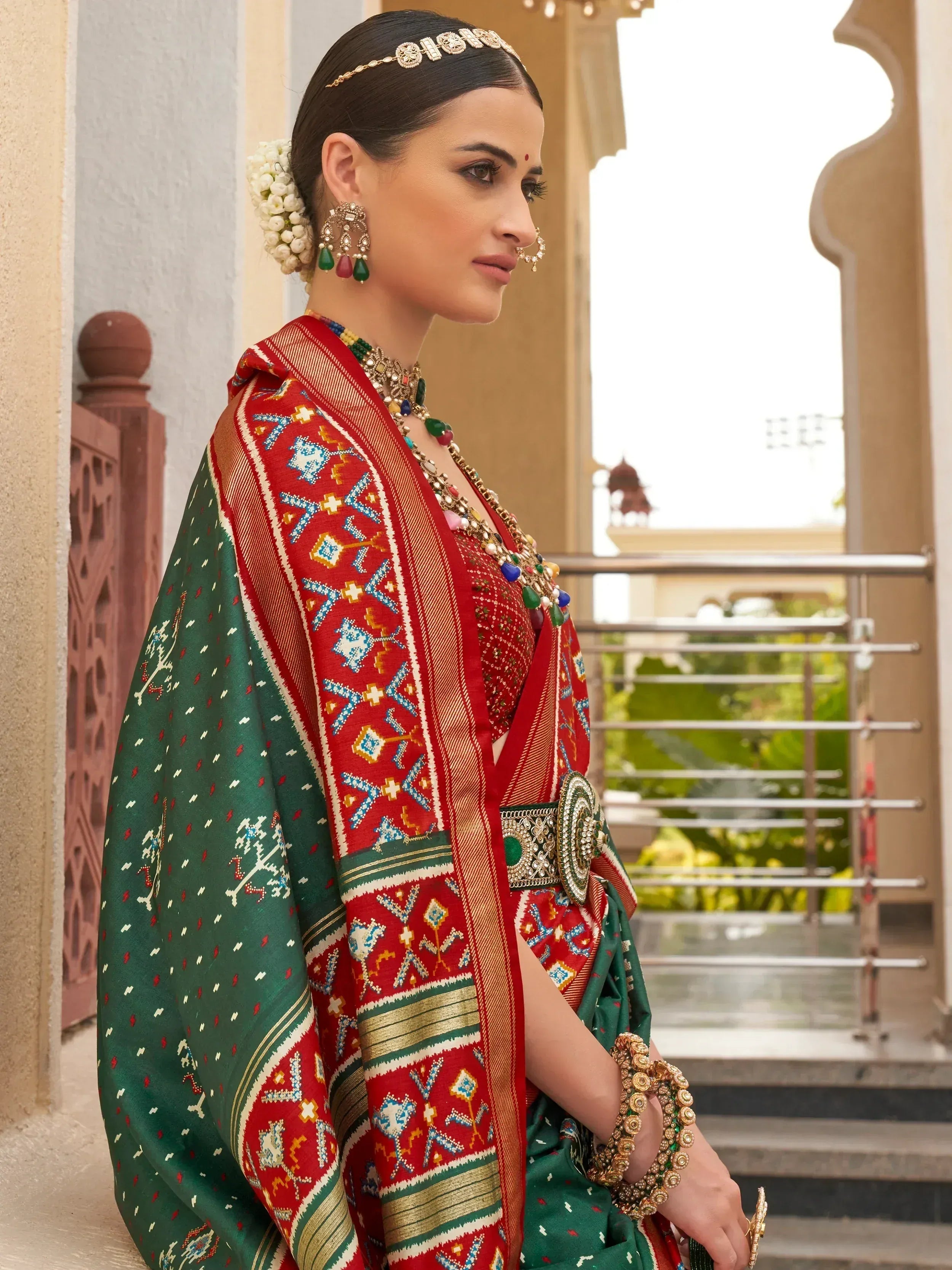 Woman in traditional red and green embroidered saree with temple jewelry, perfect for Indian ethnic wear occasions
