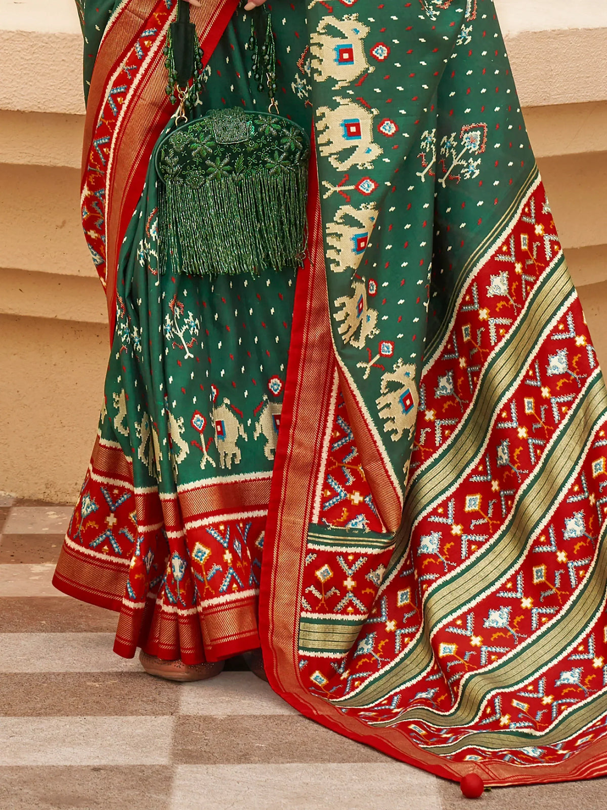 Green and red ethnic saree with elephant motifs and matching embroidered clutch