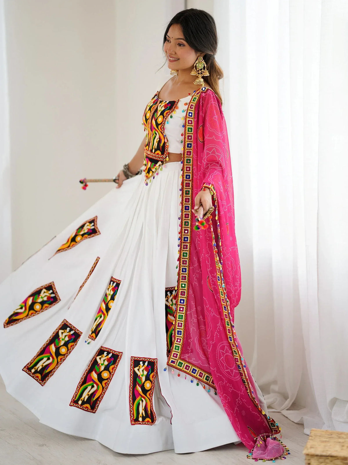 White embroidered lehenga with pink dupatta, colorful mirror work, and traditional Indian ethnic wear design
