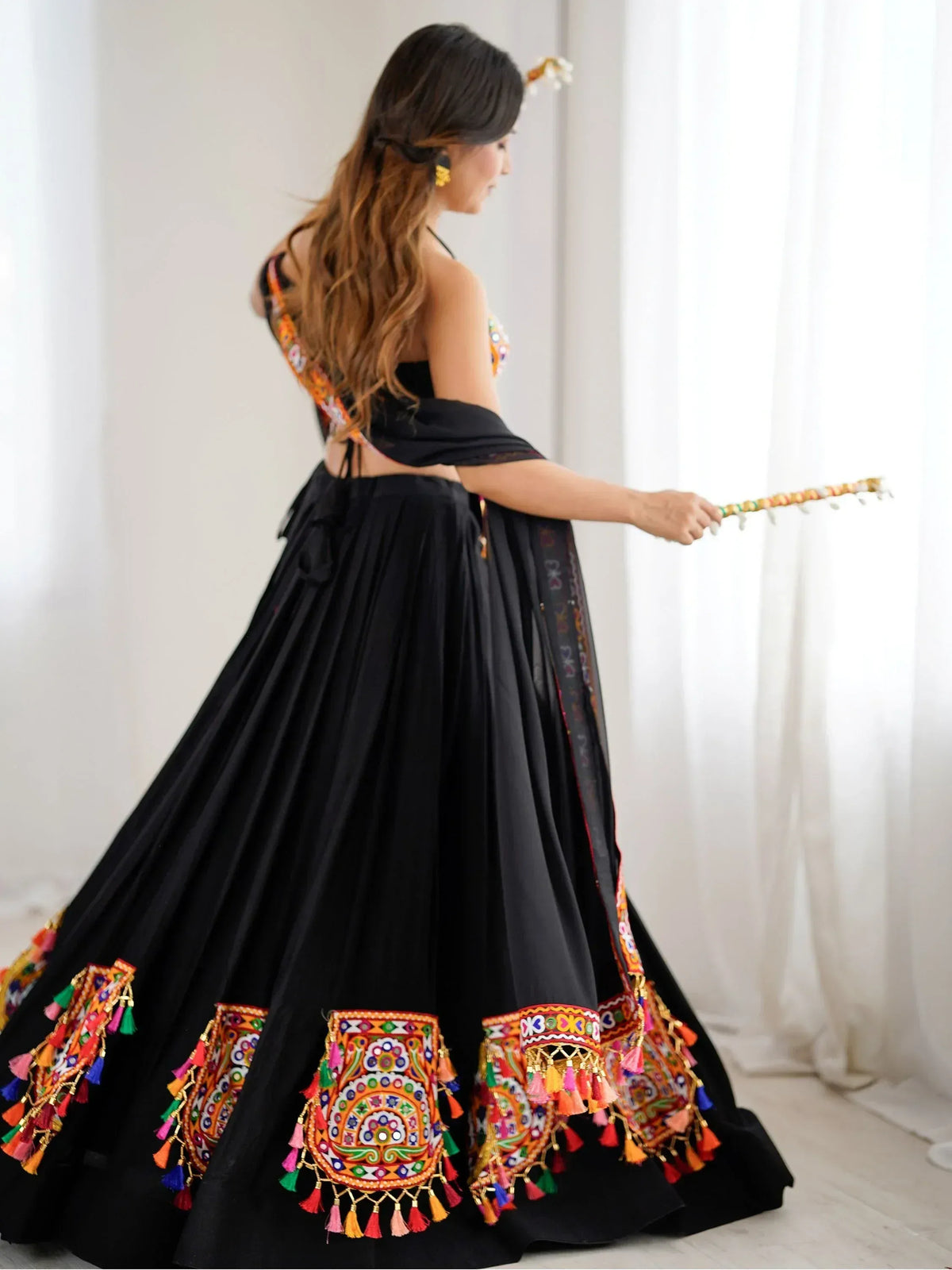 Black lehenga choli with colorful embroidery and tassels, perfect for festive occasions