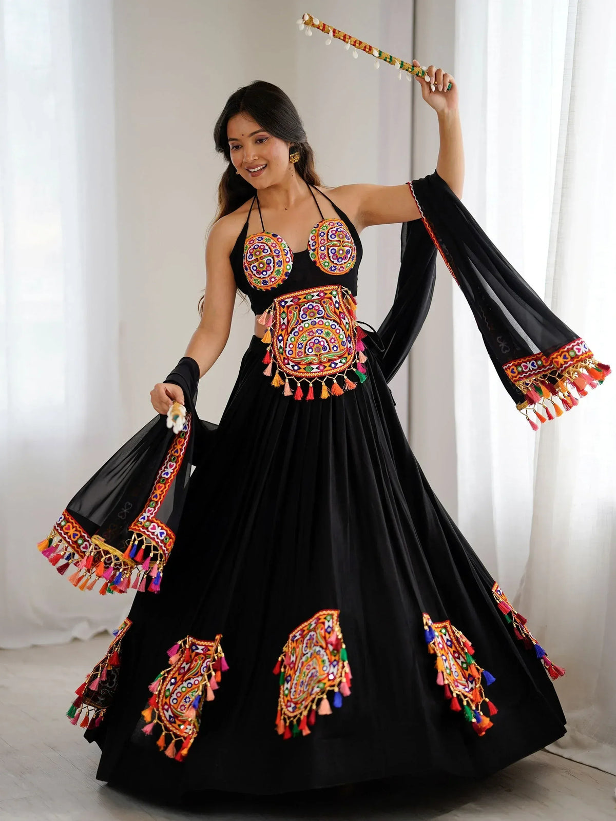 Black ethnic lehenga choli with colorful embroidery and tassels, perfect for festive occasions.