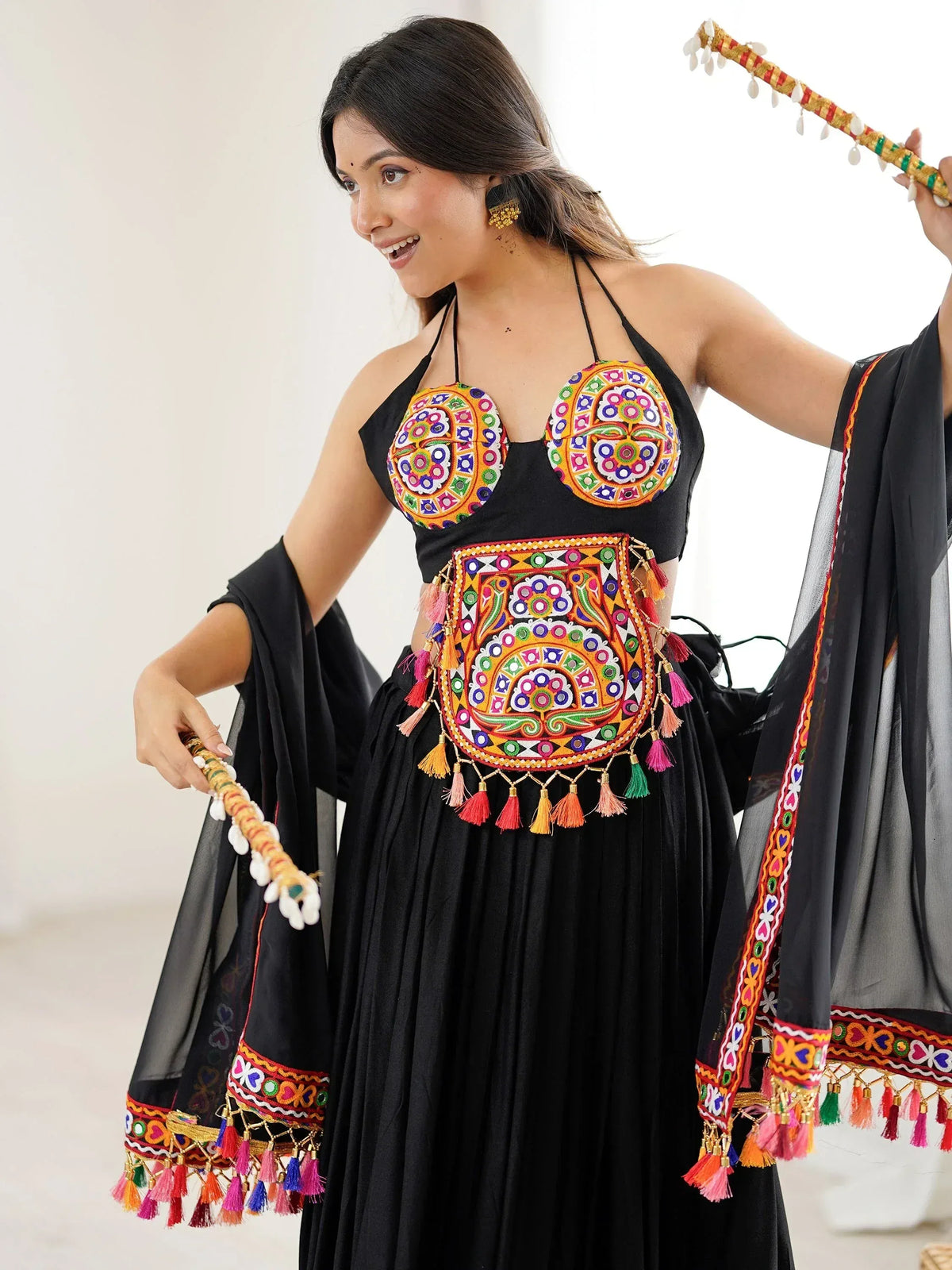 Black ethnic lehenga choli with vibrant mirror work, tassels, and dupatta for festive occasions