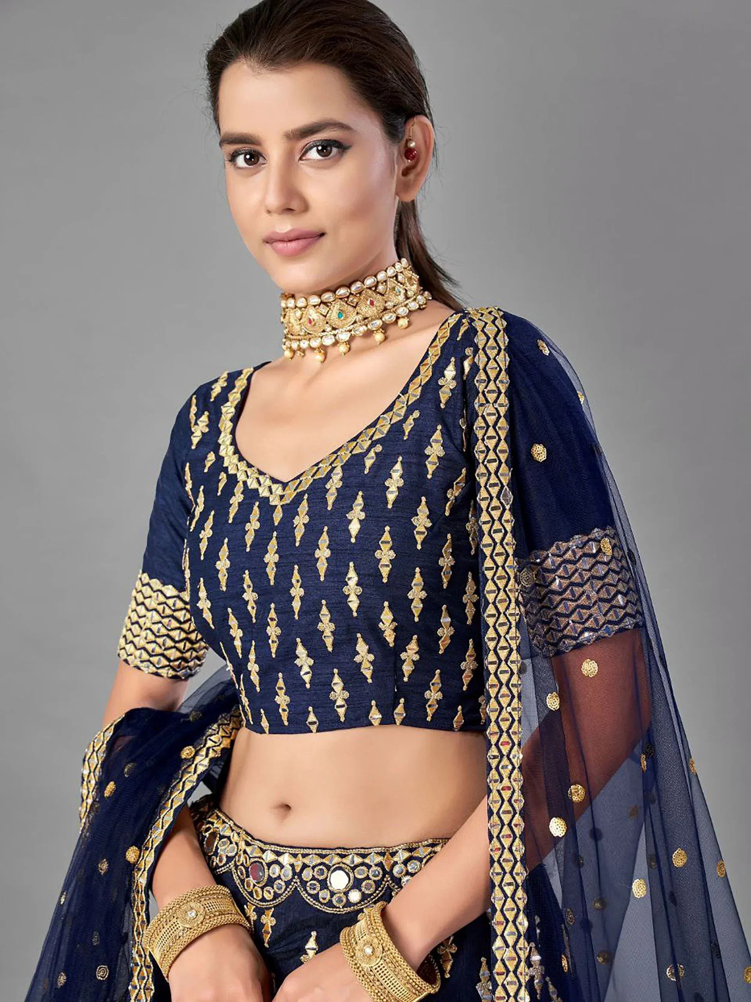 Navy blue ethnic lehenga choli with gold embroidery and mirror work, paired with matching dupatta for festive occasions.
