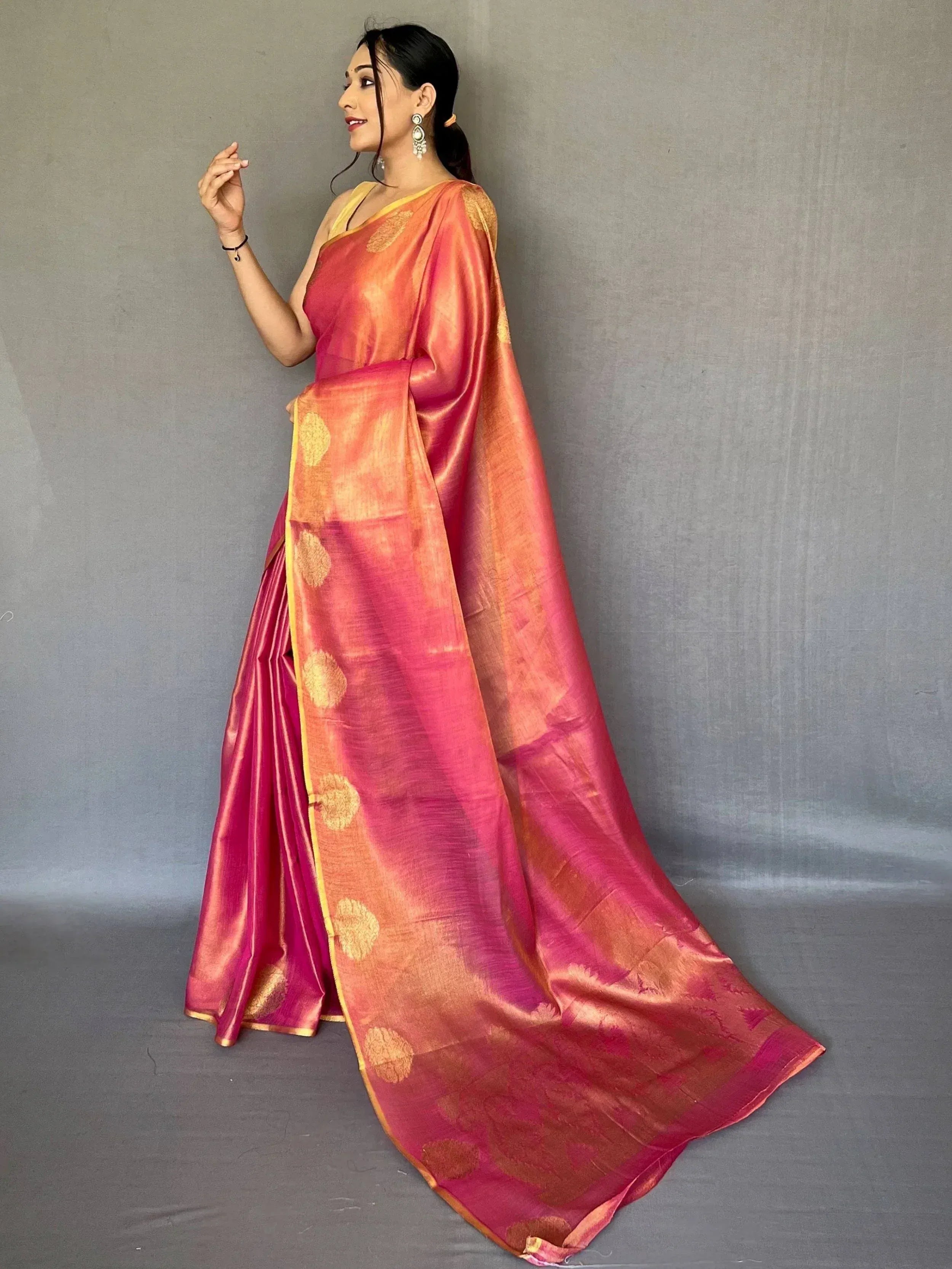 Woman in vibrant pink and orange silk saree with gold motifs, elegant ethnic wear for festive occasions