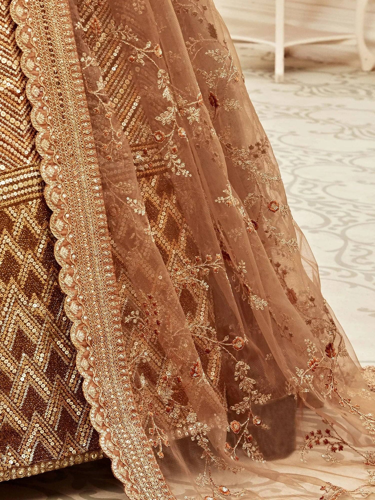 Close-up of a gold designer lehenga with intricate embroidery and sequin work