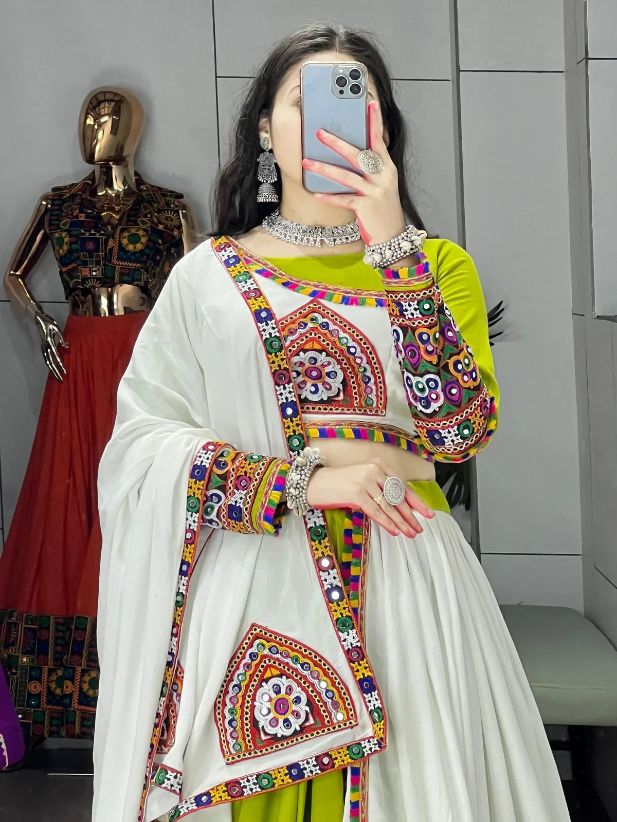 White and green embroidered ethnic wear with mirror work, styled with silver jewelry for festive occasions