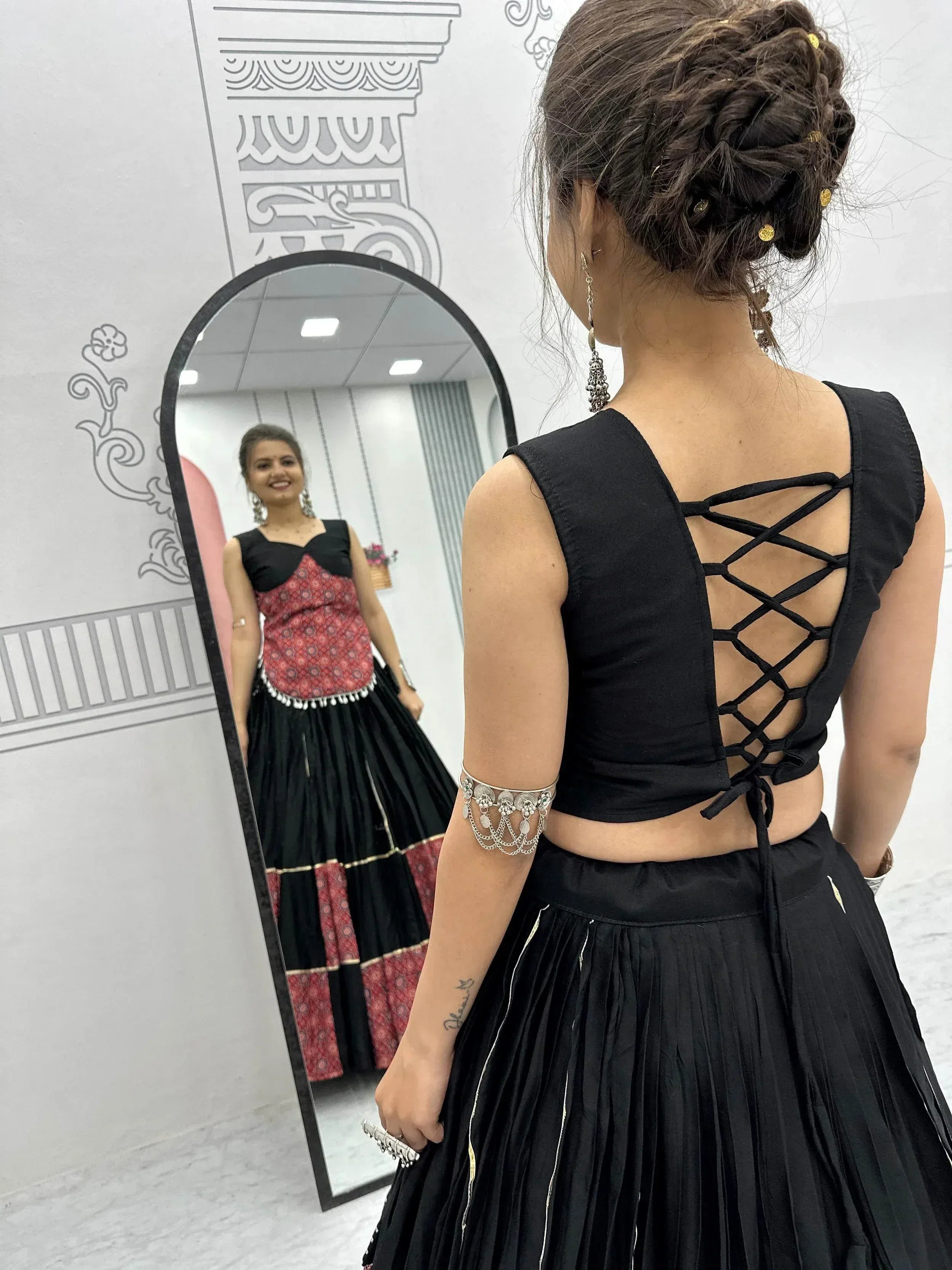 Black ethnic lehenga choli with crisscross back blouse, mirror reflection, and traditional jewelry