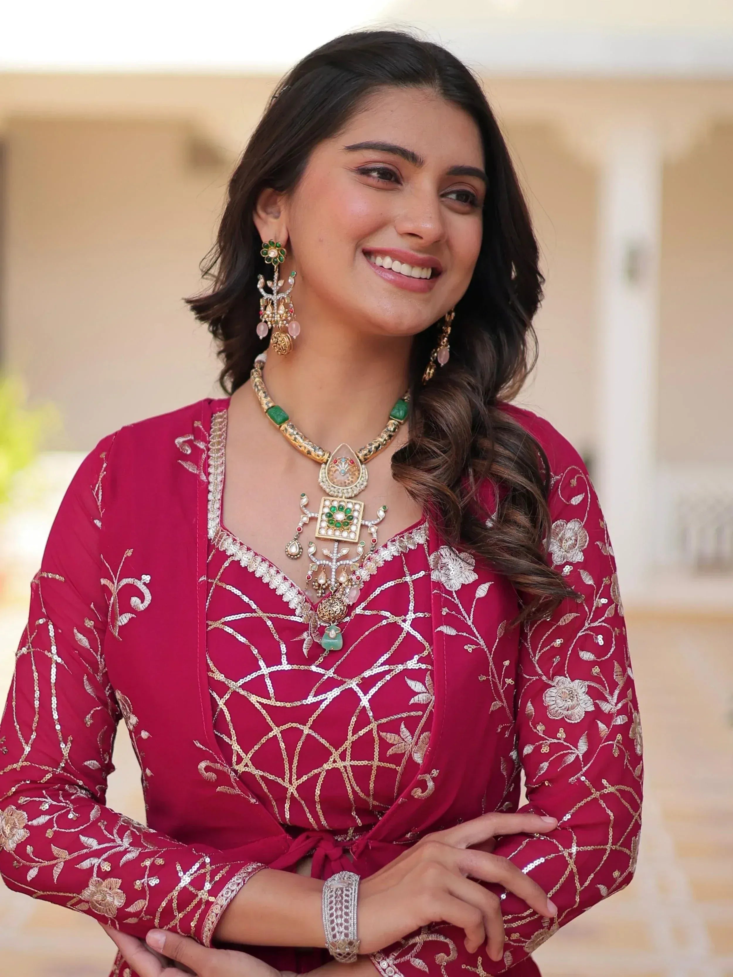 Elegant woman in maroon embroidered ethnic gown with gold jewelry and floral patterns