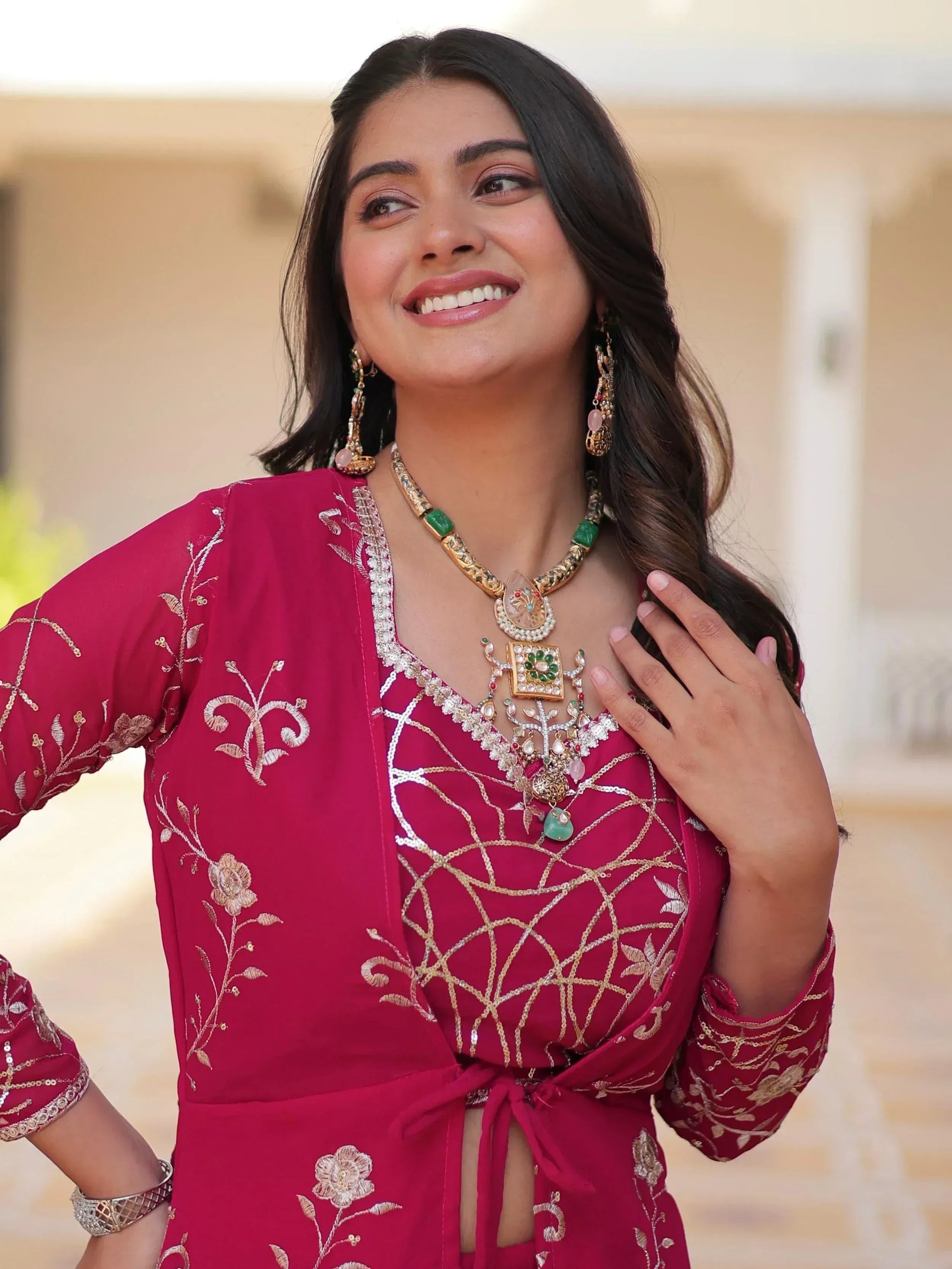 Woman in maroon embroidered ethnic gown with gold jewelry, perfect for Indian festive occasions