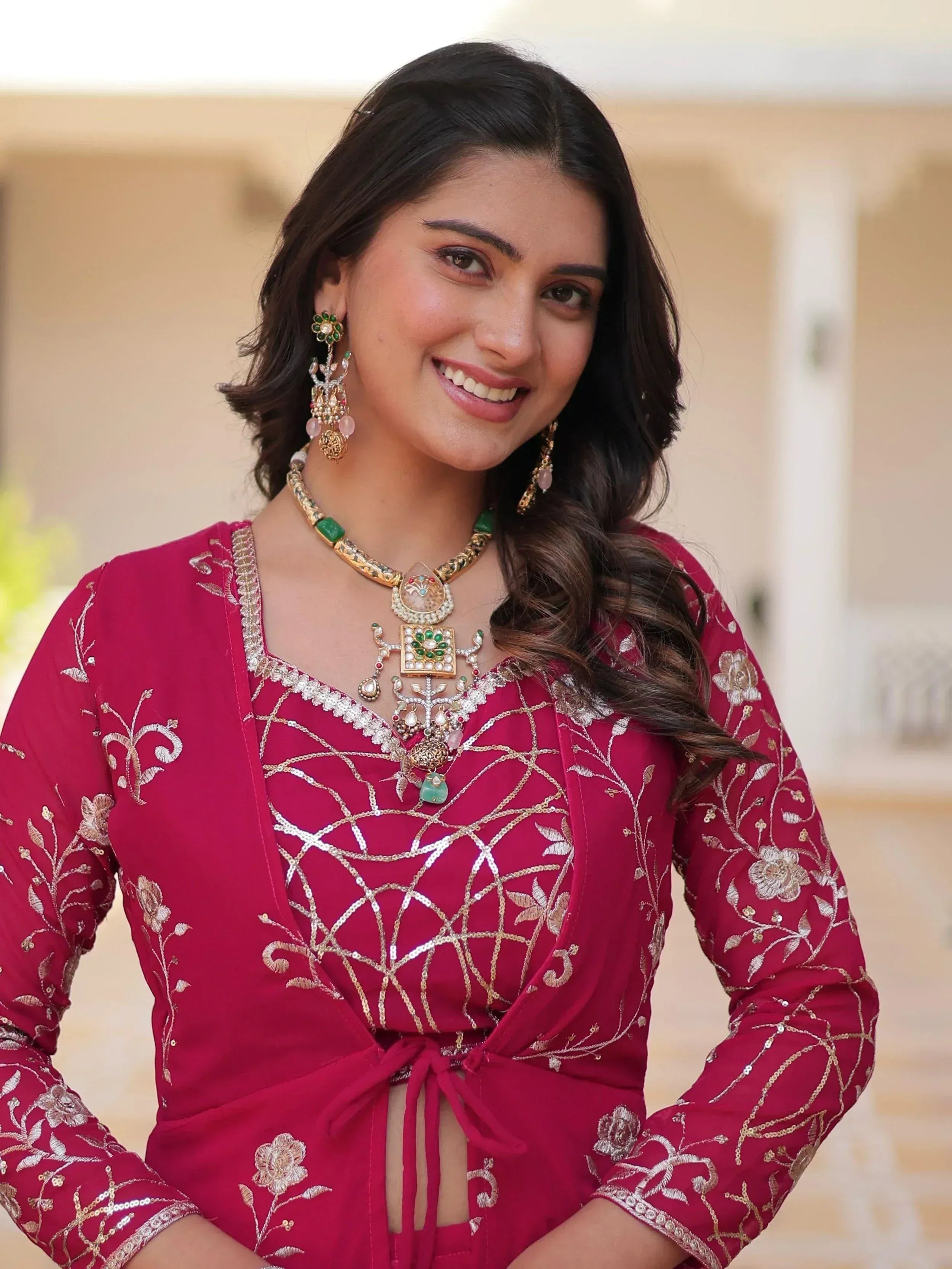 Woman in maroon embroidered ethnic gown with gold jewelry, perfect for Indian occasions and festive wear.