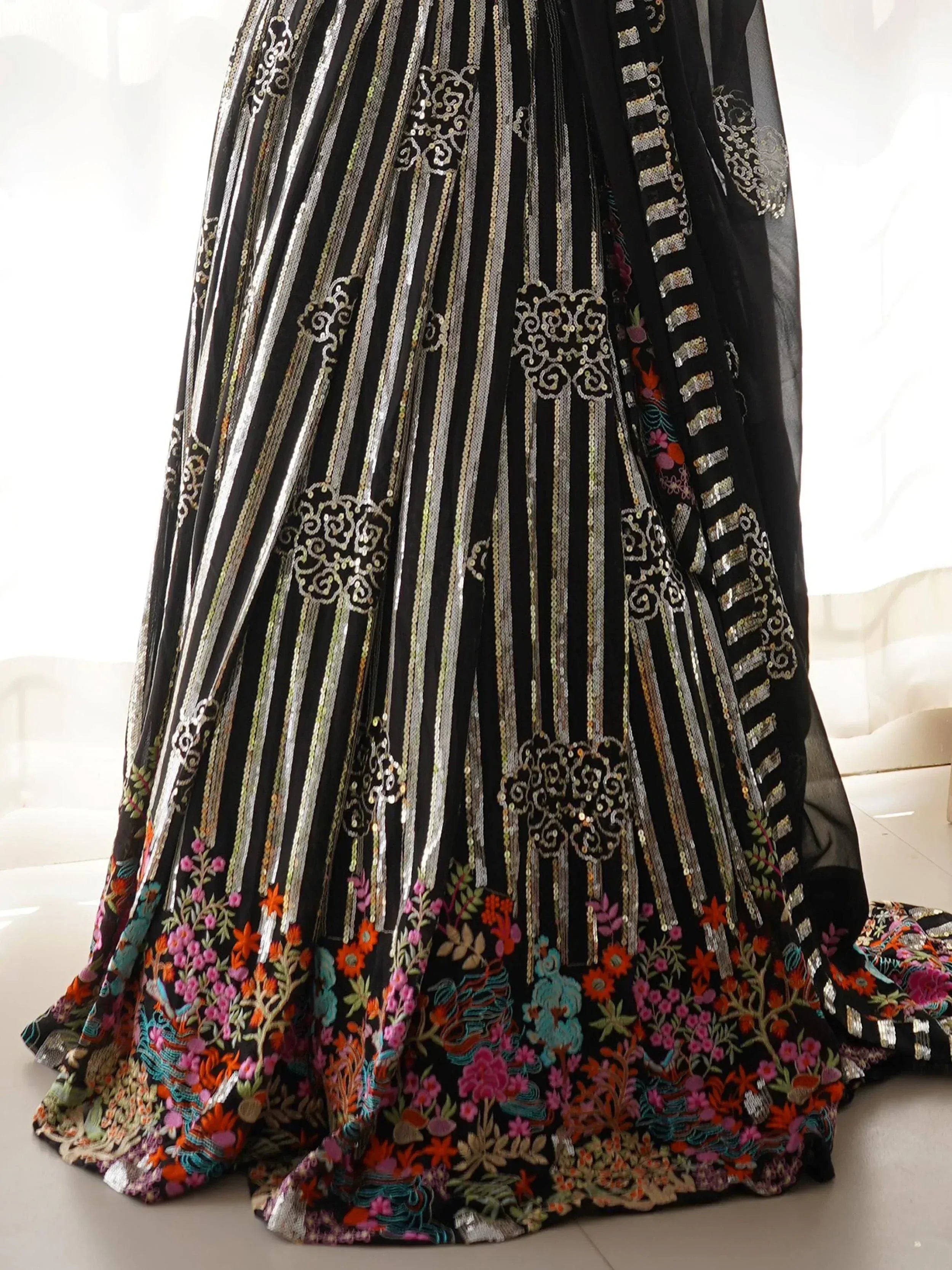 Black ethnic gown with silver stripes, floral embroidery, and sequin detailing for festive occasions.