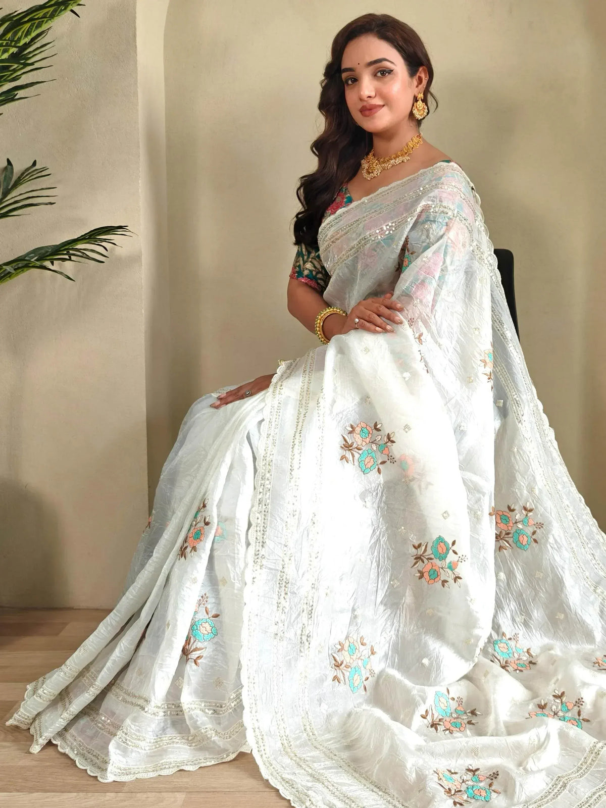White floral embroidered saree with sequin border, styled with gold jewelry for ethnic occasions