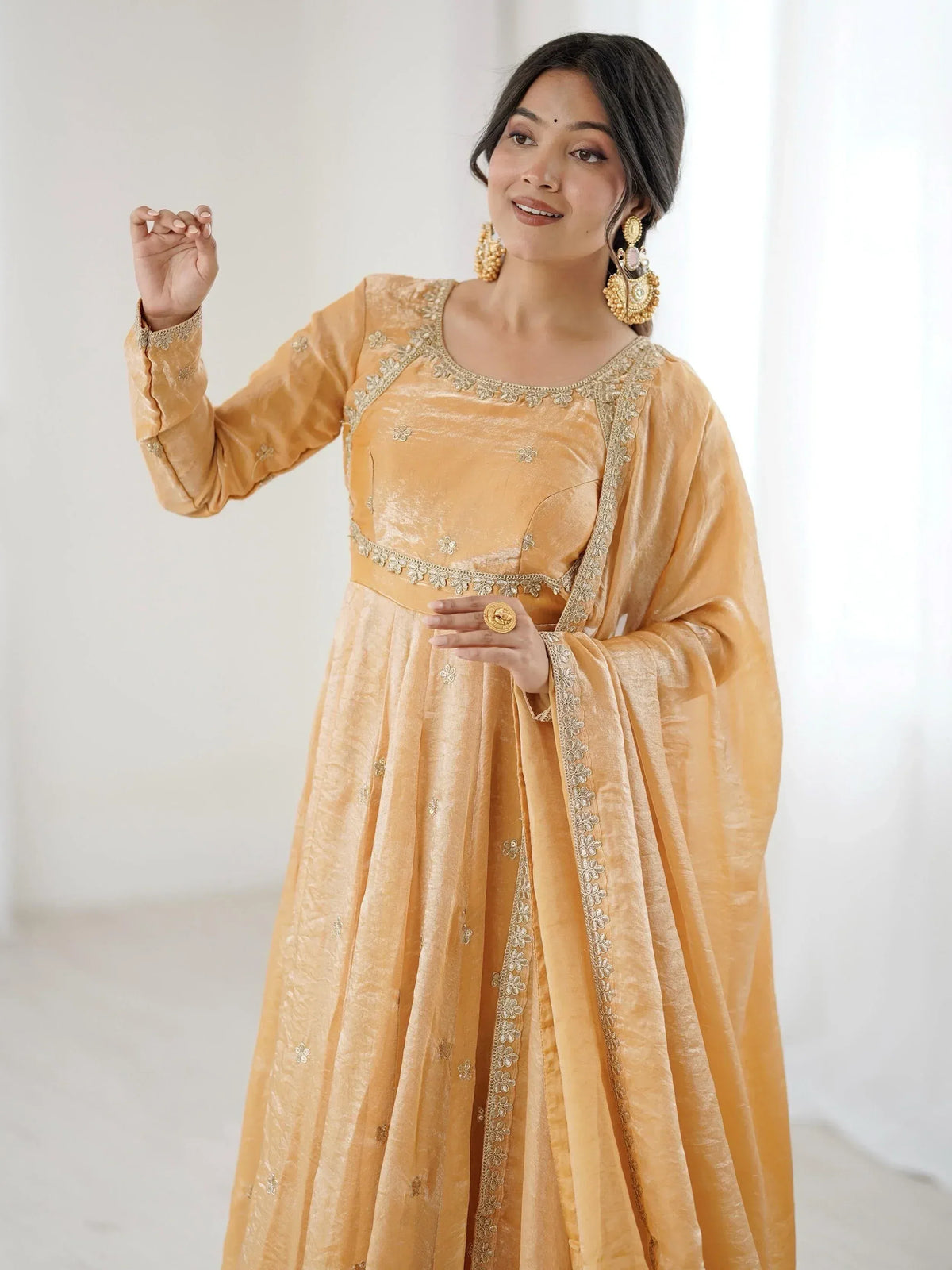 Elegant mustard yellow ethnic gown with floral embroidery and gold detailing, perfect for festive occasions.