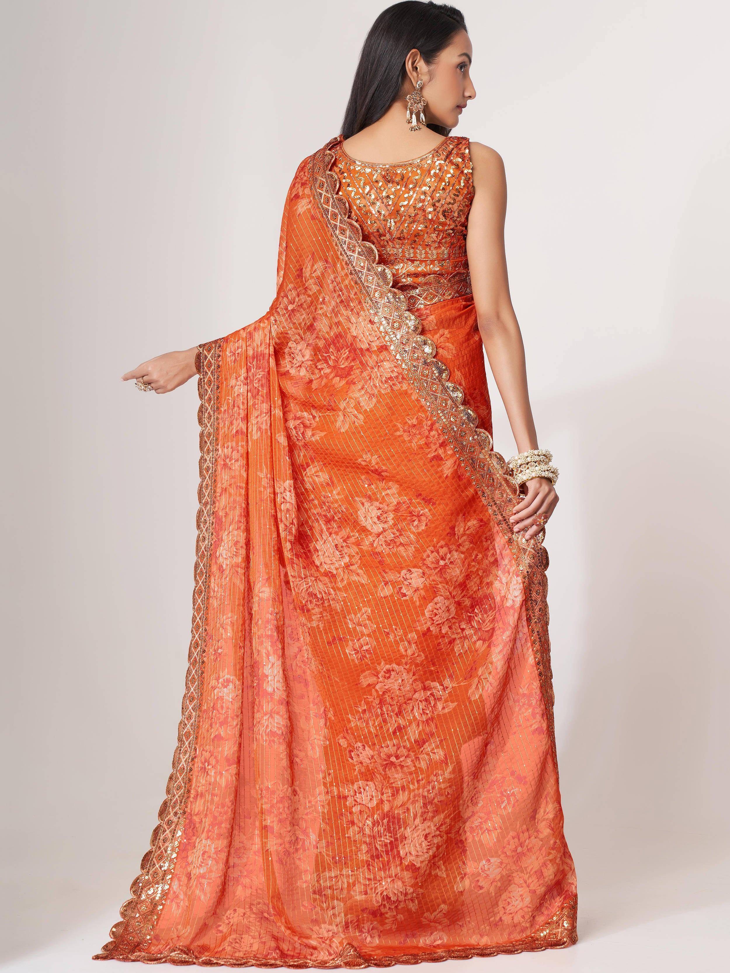 Orange floral saree with gold embroidery and sequin work, styled with statement jewelry for ethnic occasions