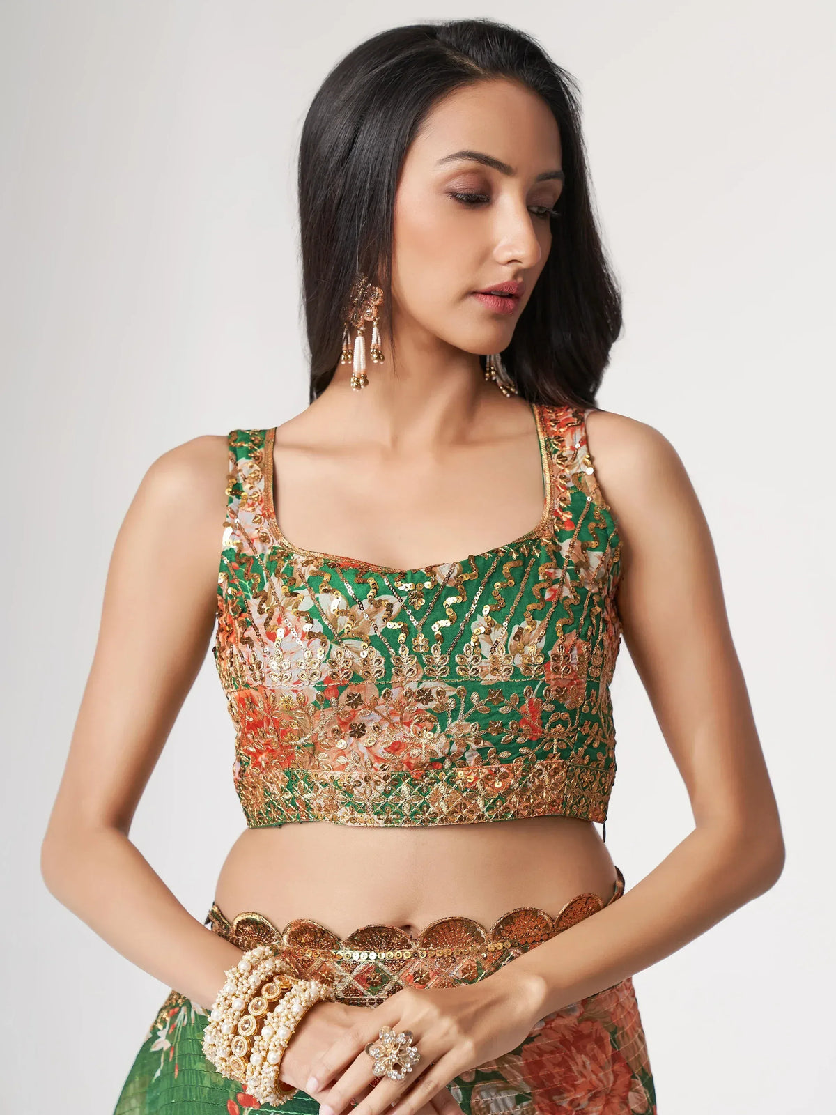 Green floral embroidered lehenga choli with gold sequins and matching jewelry for Indian ethnic wear