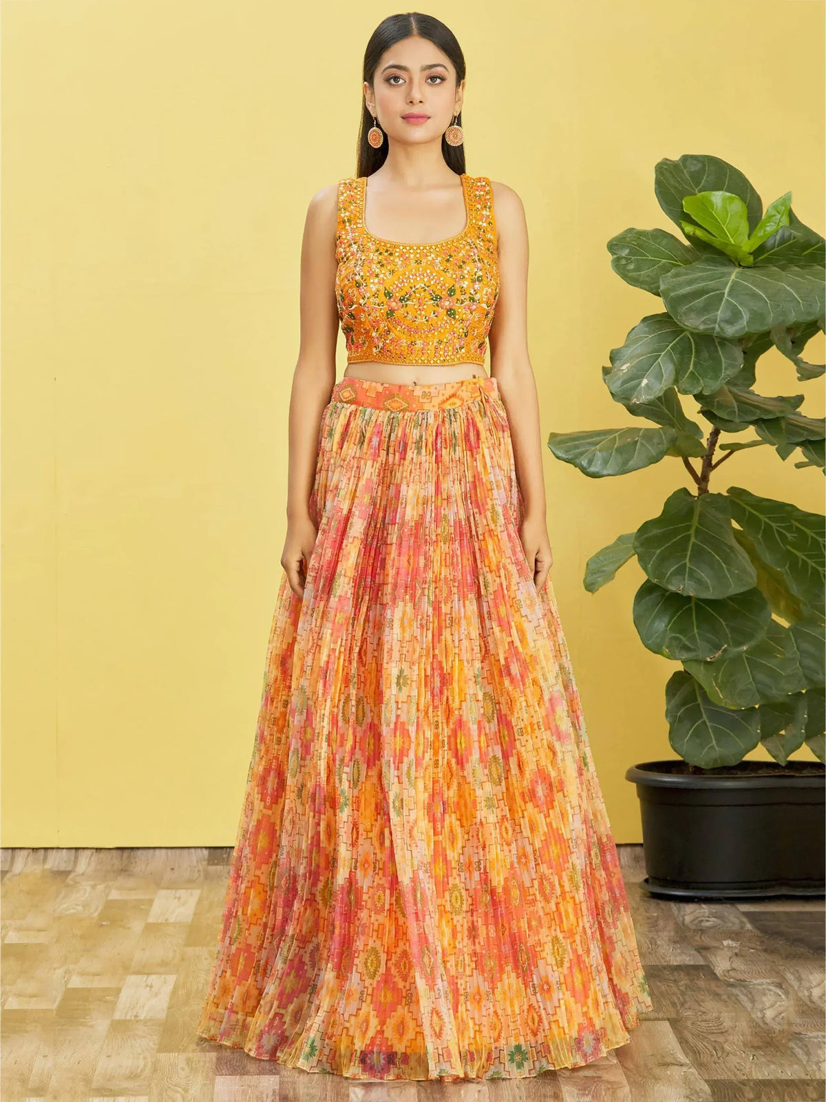 Woman in vibrant orange embroidered crop top and pleated printed skirt, Indian ethnic wear