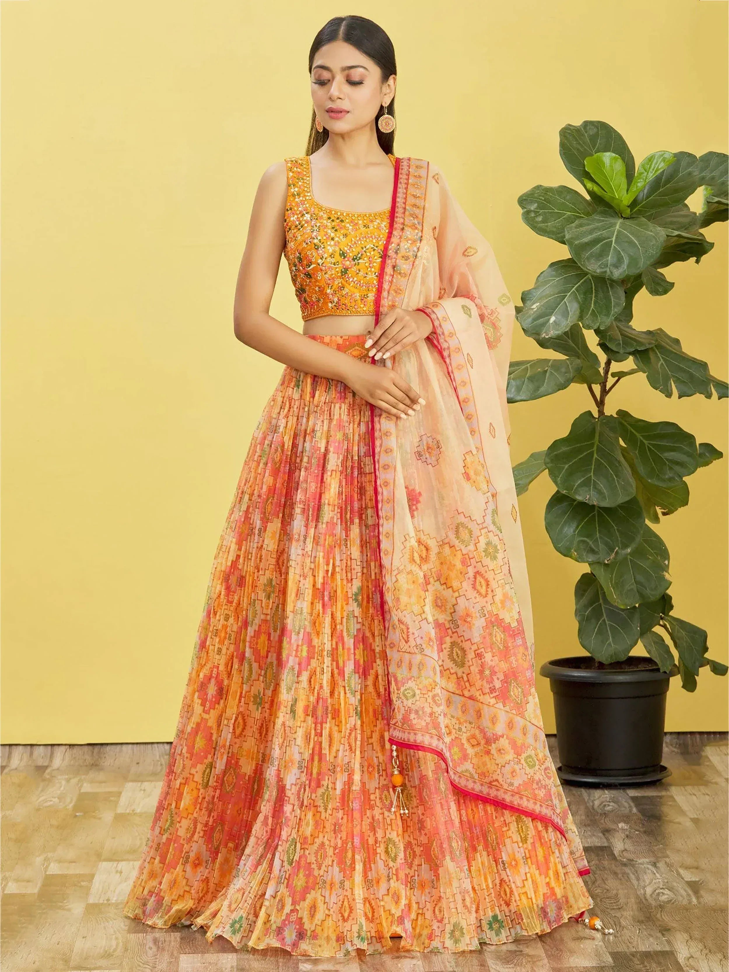 Woman in vibrant orange and pink printed lehenga choli with floral embroidery, perfect for Indian ethnic occasions