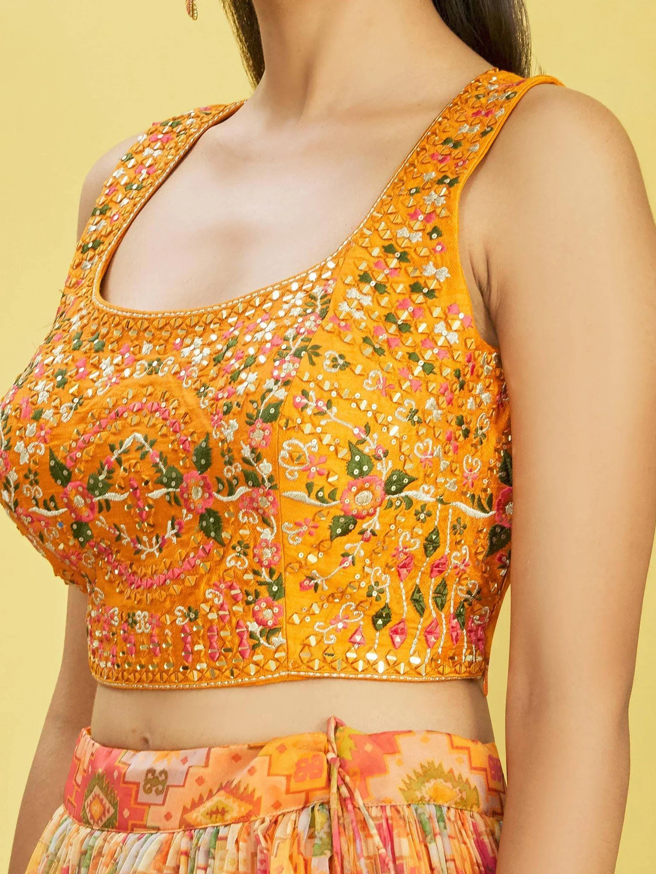 Vibrant yellow embroidered blouse with floral mirror work, paired with colorful printed skirt