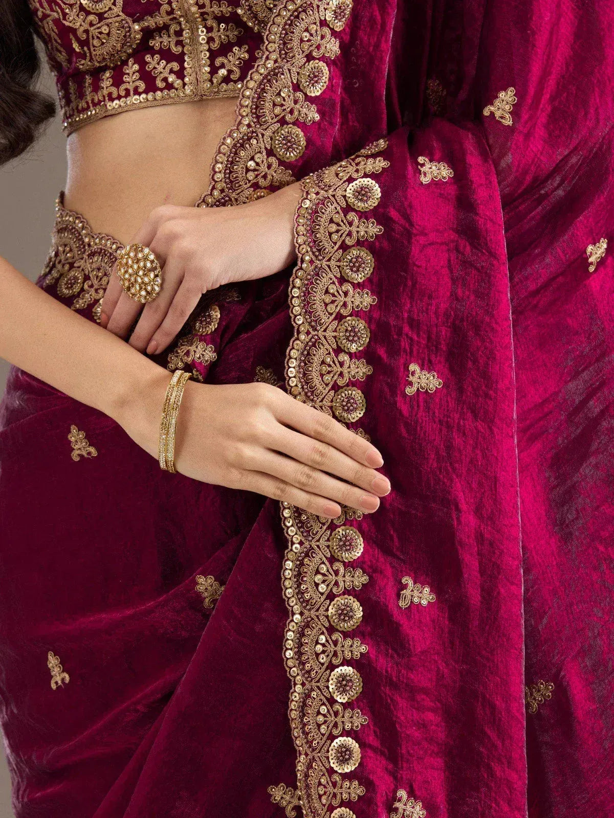 Rich maroon velvet saree with intricate gold embroidery and embellished border, perfect for Indian ethnic wear.