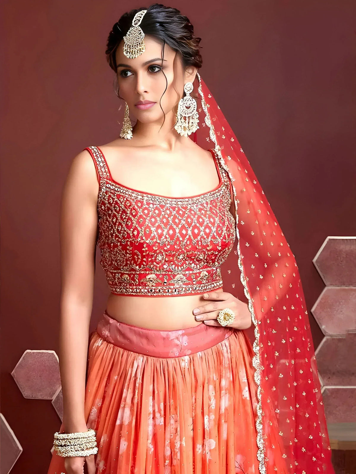 Red and orange embroidered lehenga choli with gold detailing and matching dupatta, perfect for Indian weddings and festive occasions.
