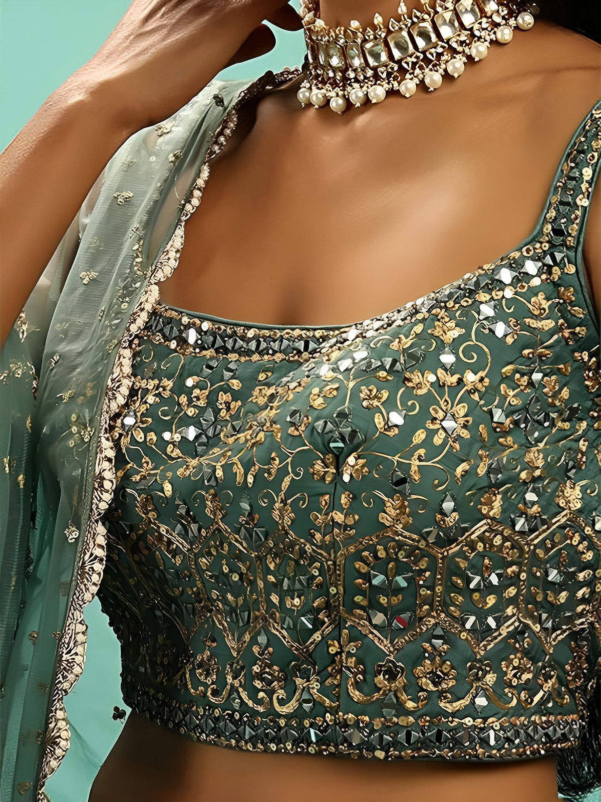 Emerald green embroidered blouse with gold floral motifs and mirror work, paired with a sheer dupatta.