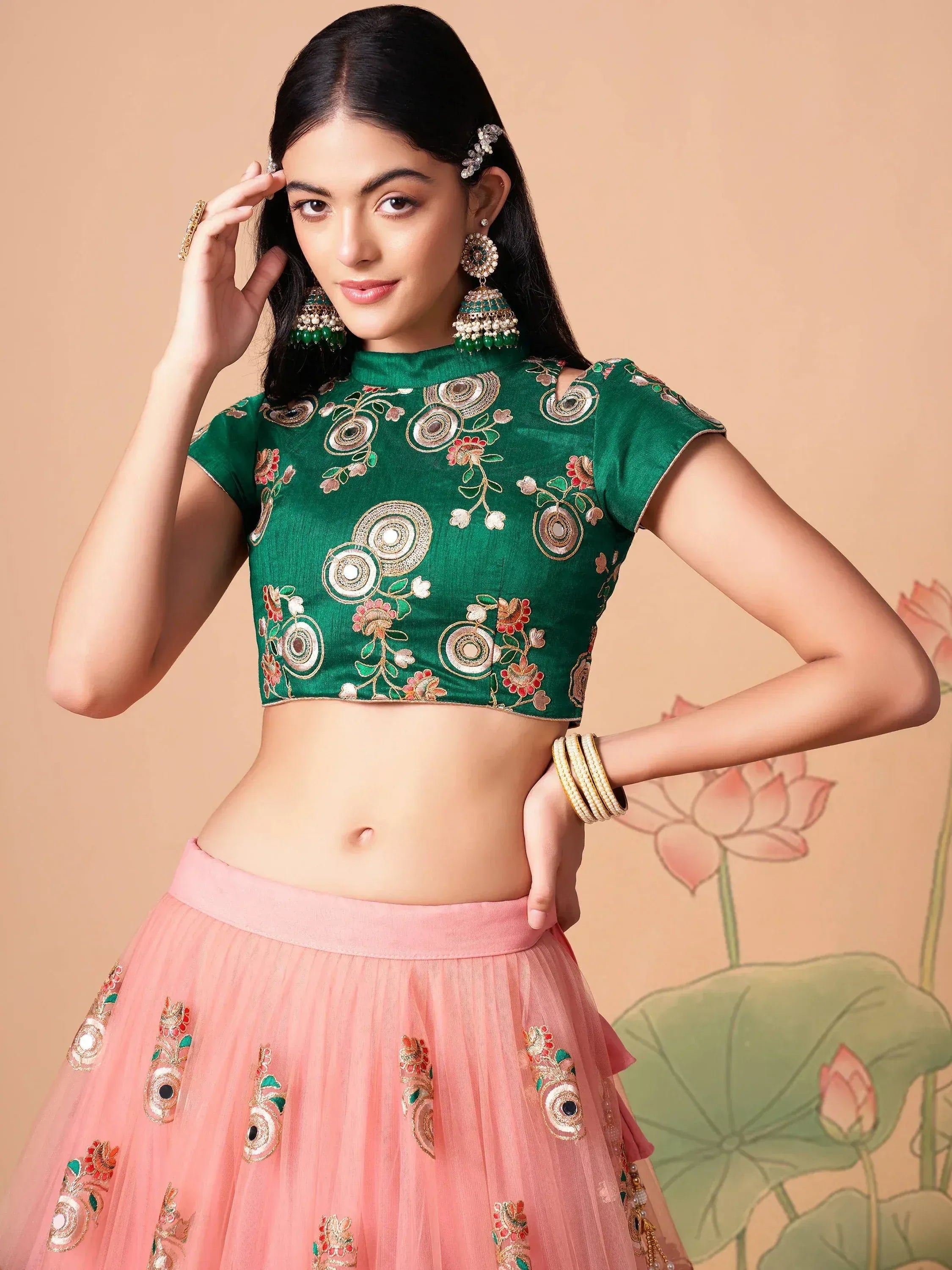 Green embroidered crop top with pink lehenga, floral motifs, and traditional Indian jewelry for festive occasions.